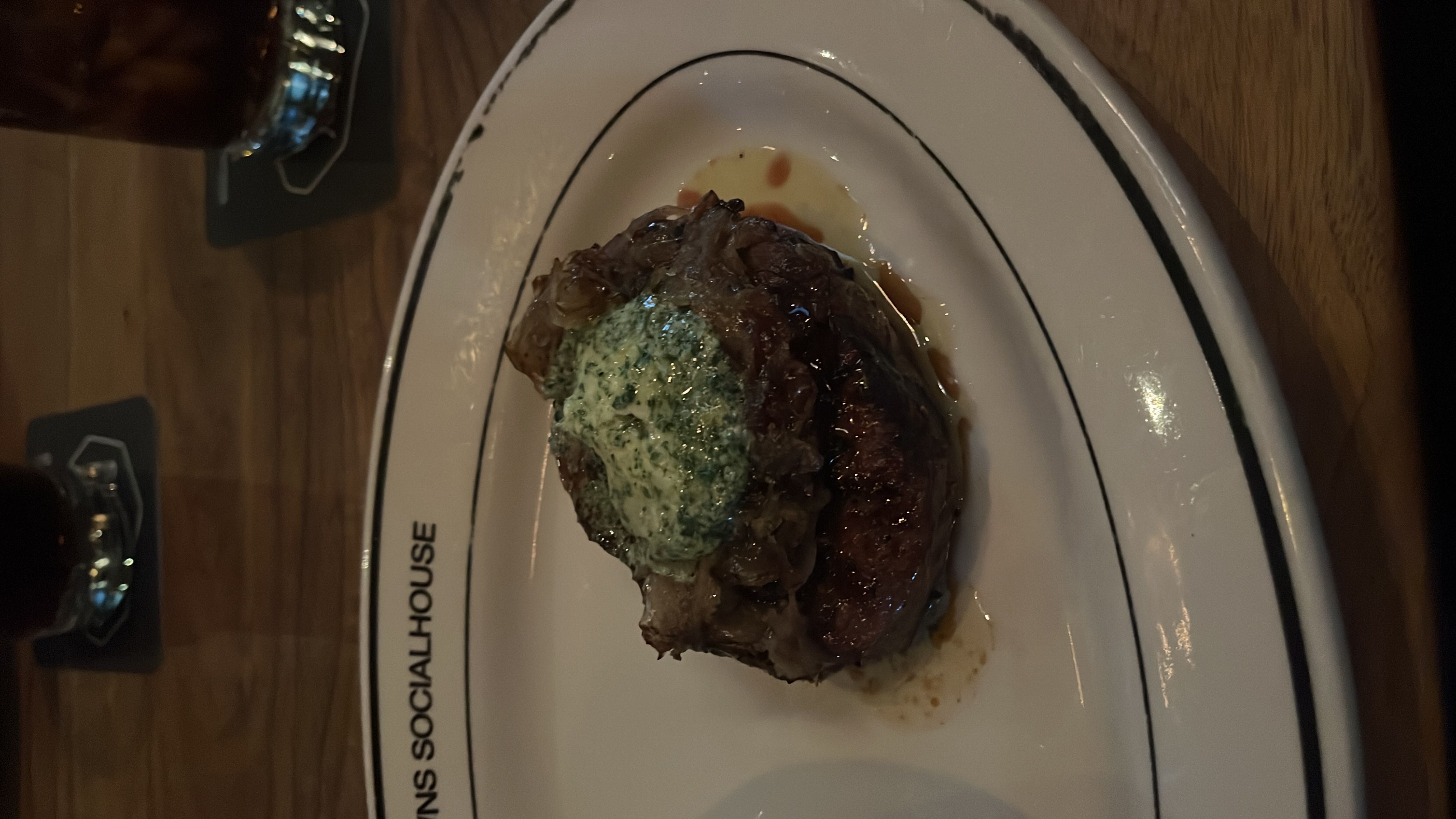 A steak dish topped with herb butter and caramelized onions, served on a plate.