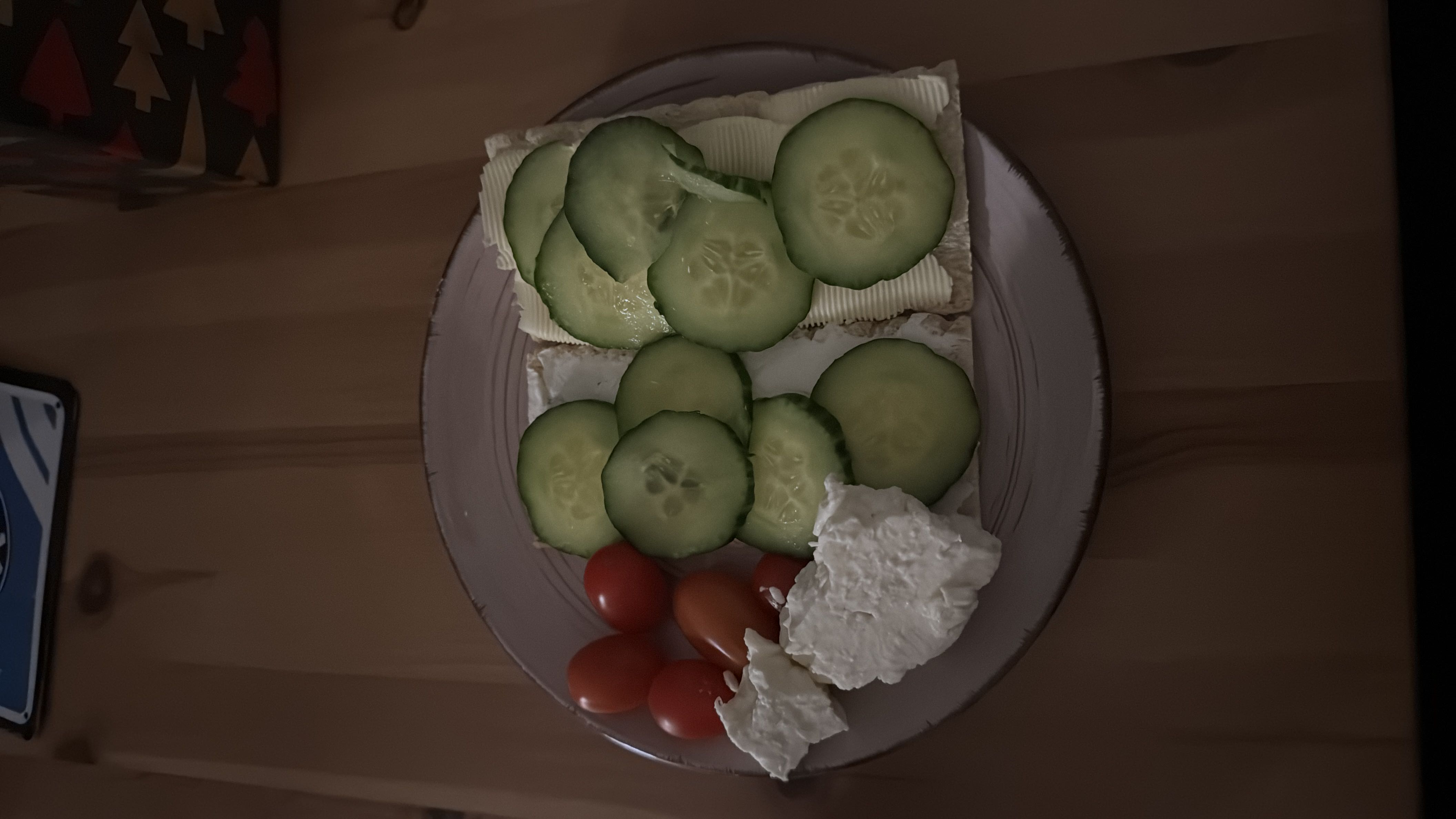 A light meal consisting of crispbread topped with cucumber slices, served with cherry tomatoes and cheese.