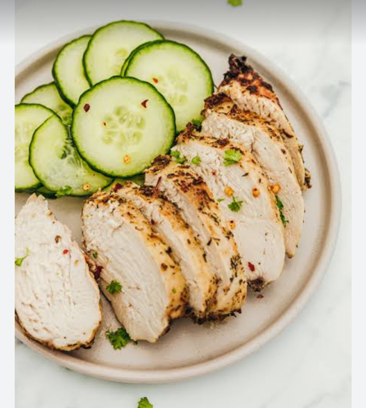 A healthy dish featuring grilled chicken breast and fresh cucumber slices, low in carbs and high in protein.