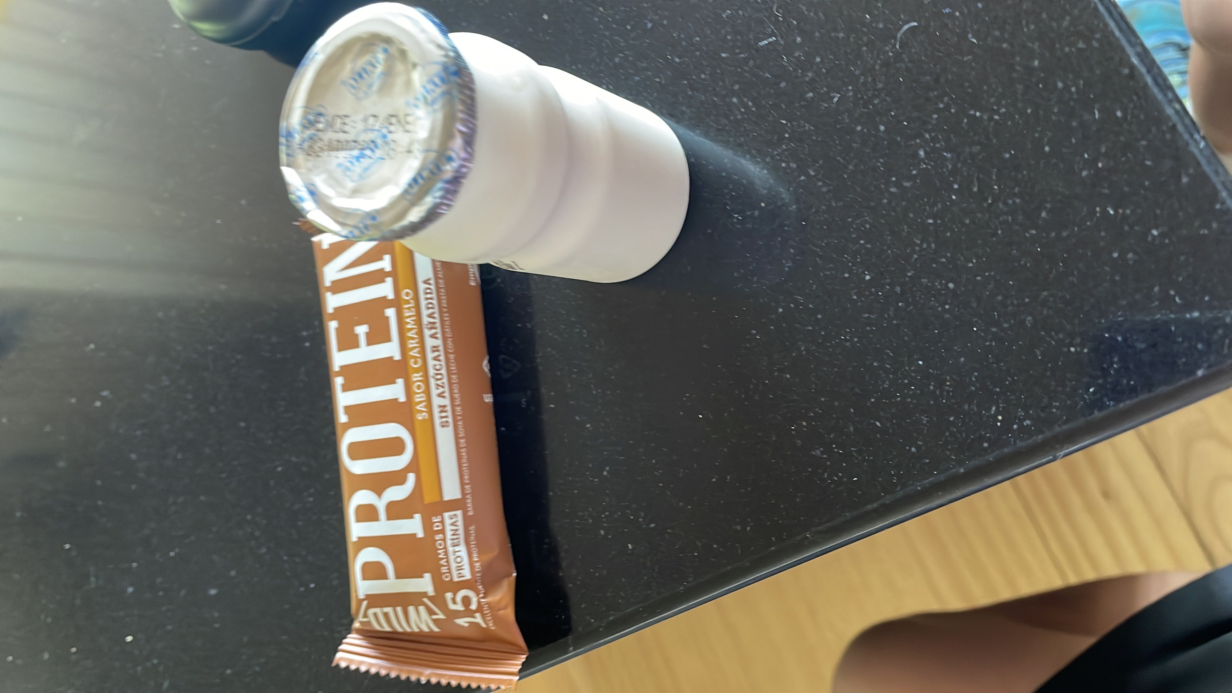 The image shows a caramel-flavored protein bar with 15 grams of protein and a yogurt drink, both suitable for a high-protein snack.