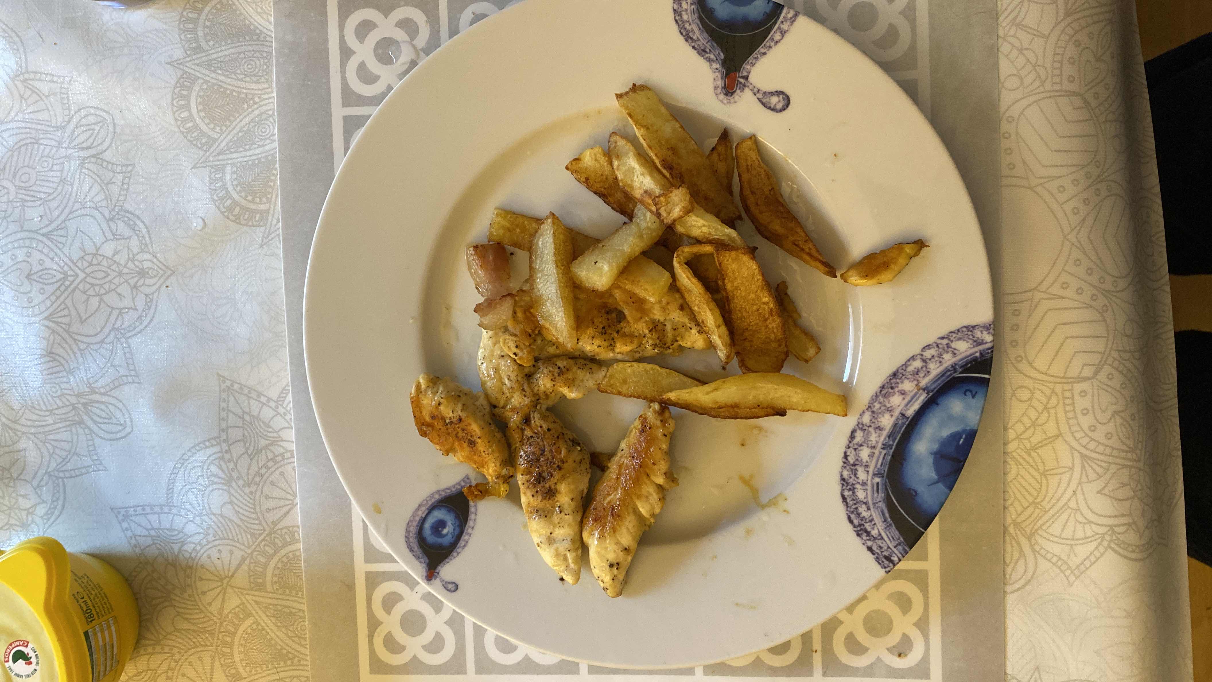 A plate containing grilled chicken breast and fried potato wedges, seasoned with spices.