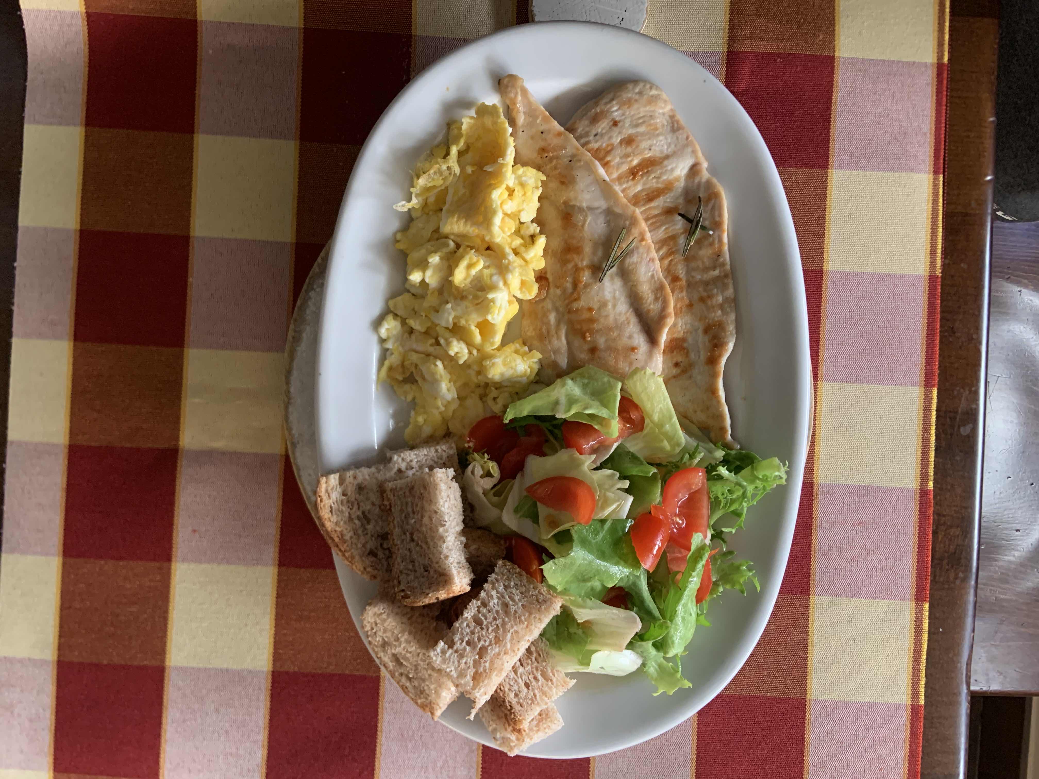 A balanced meal consisting of grilled chicken, scrambled eggs, fresh salad, and whole grain bread.