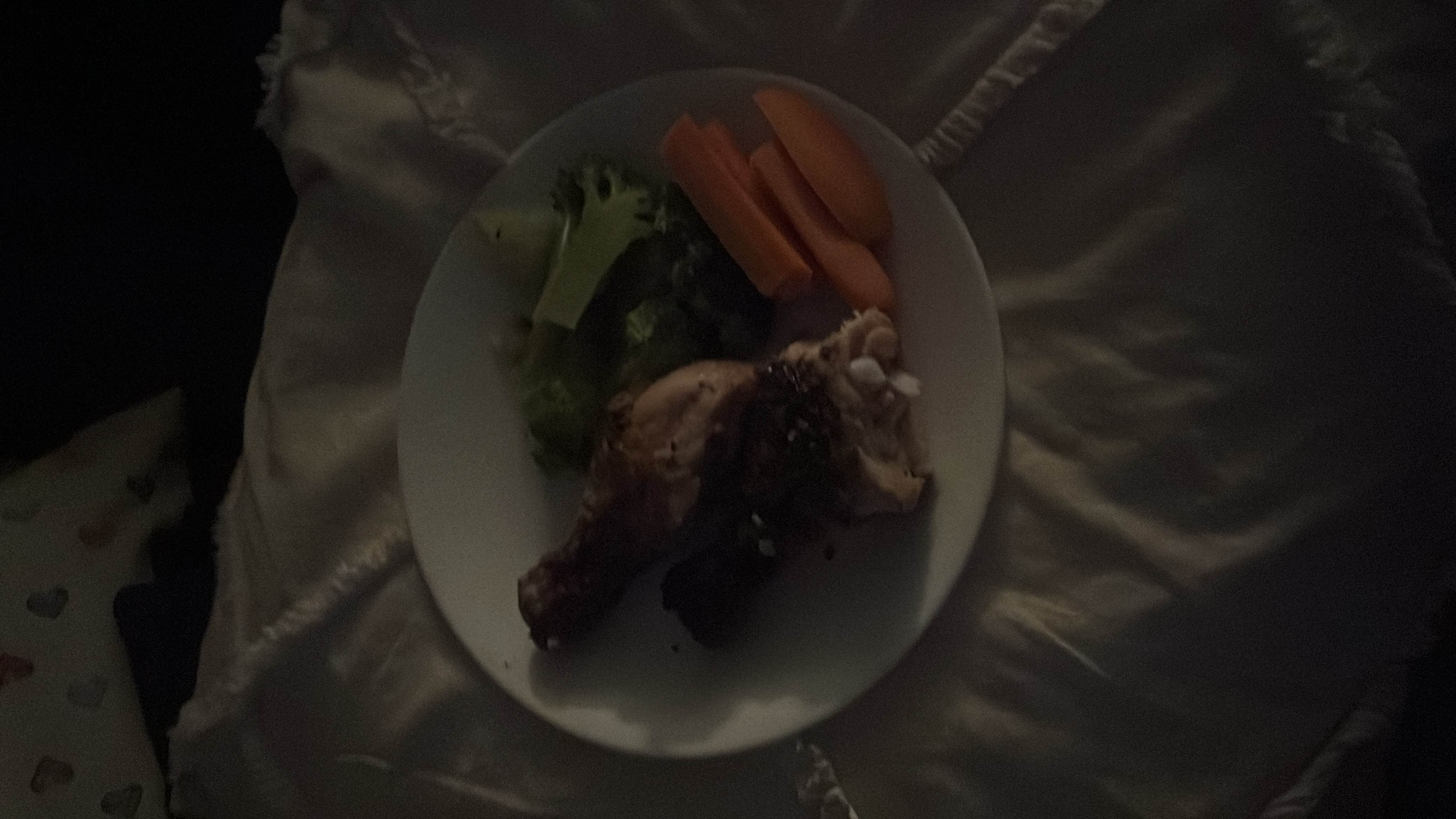 A balanced meal consisting of a grilled chicken drumstick, steamed broccoli, and raw carrots.