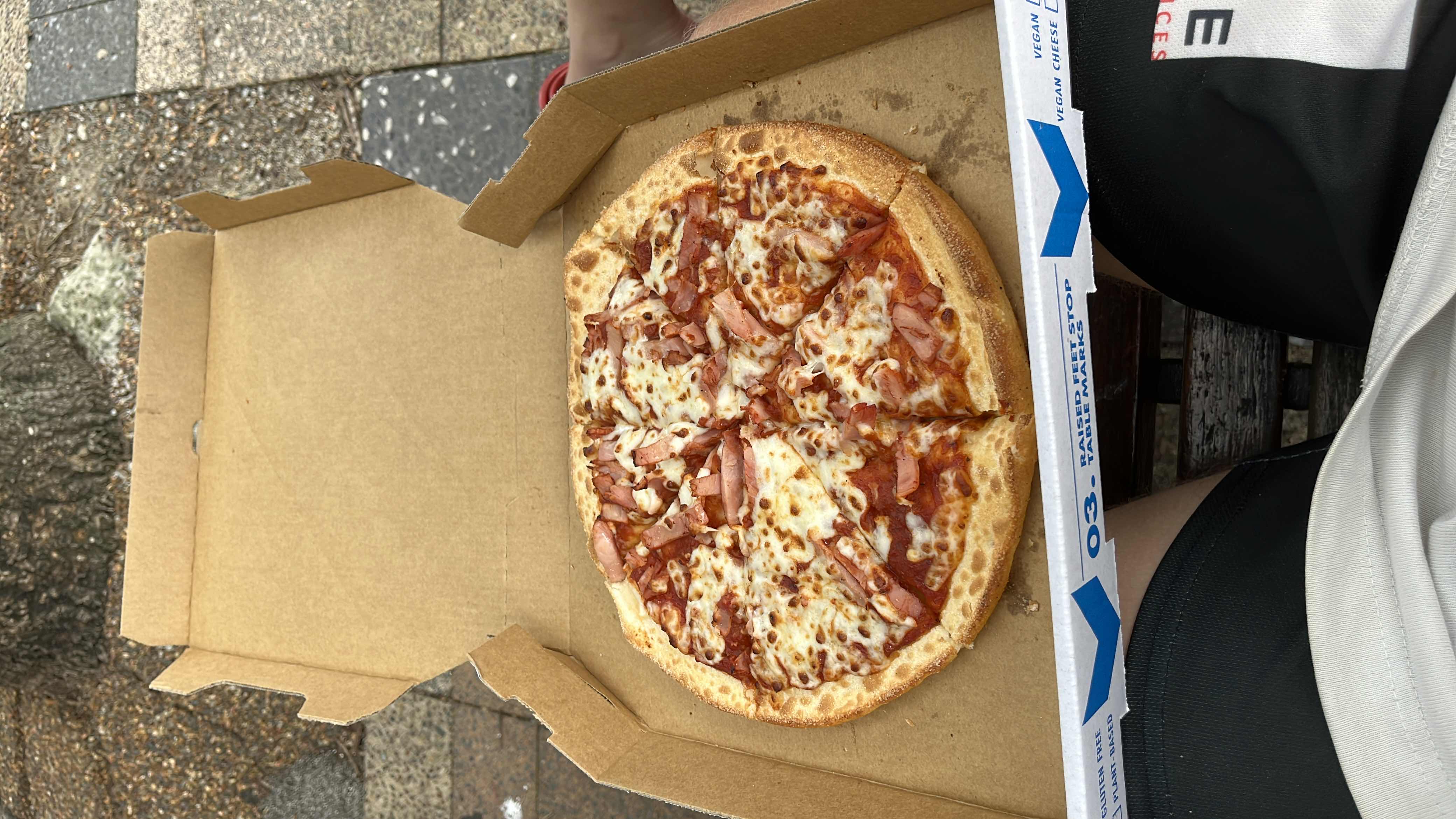 A medium-sized ham and cheese pizza with a crispy crust, topped with tomato sauce, melted cheese, and slices of ham.