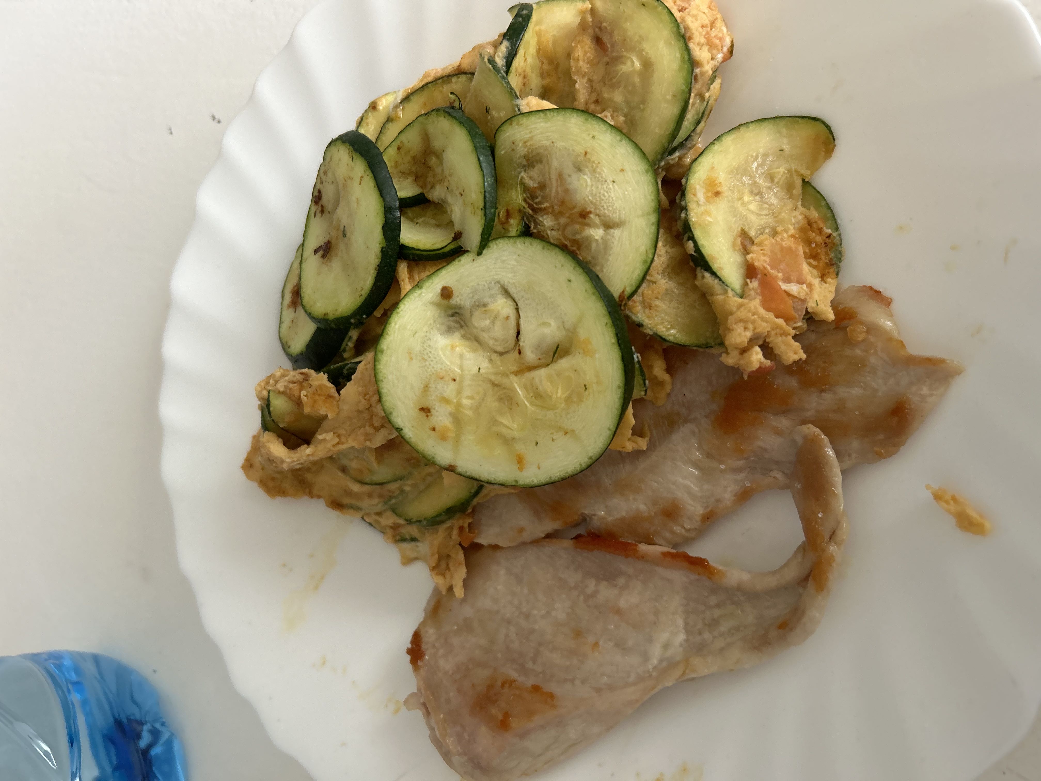 A healthy dish consisting of grilled chicken breast, sautéed zucchini slices, and scrambled eggs.