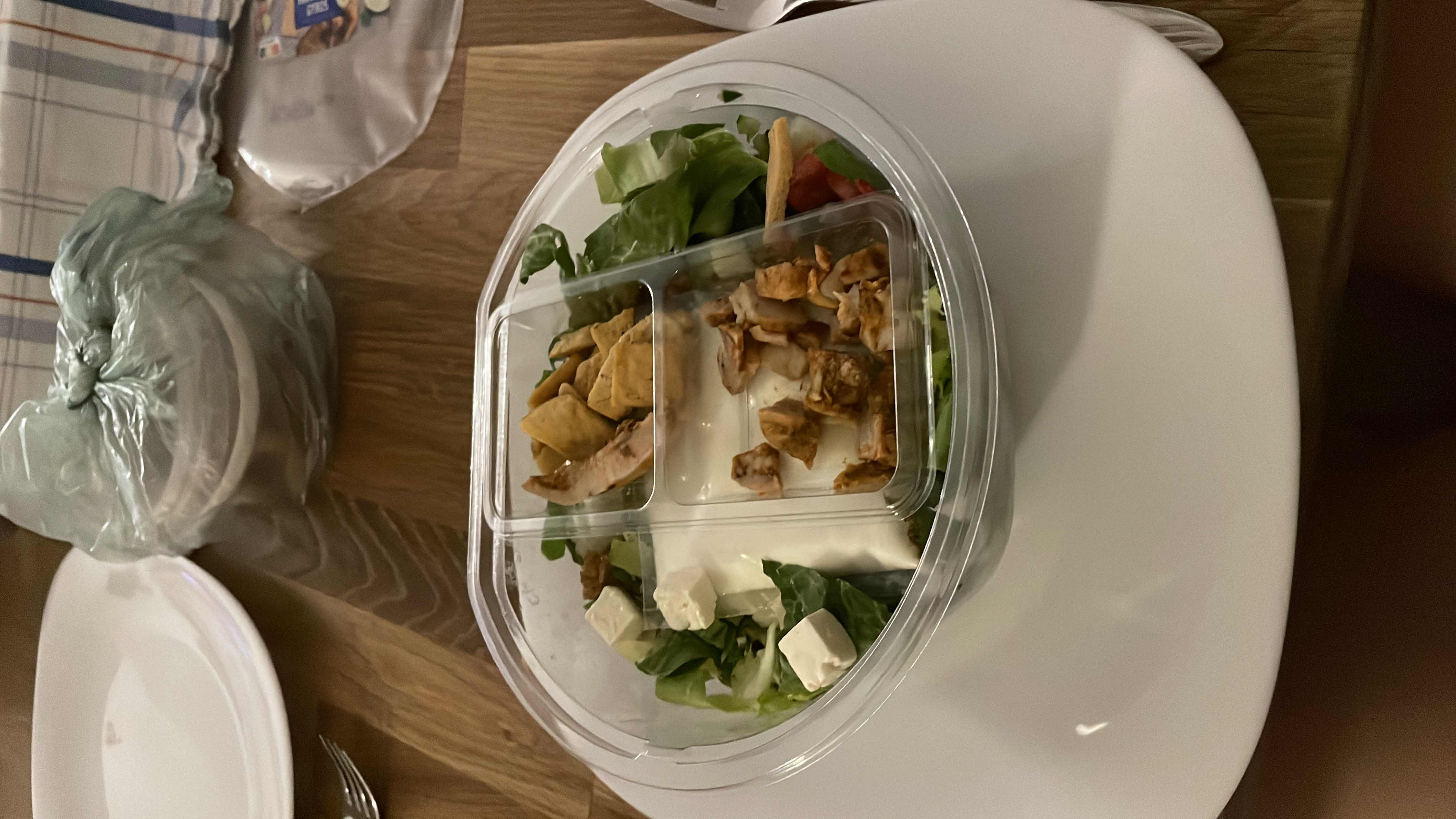 A healthy salad with lettuce, feta cheese, grilled chicken, and croutons, served with a creamy dressing.