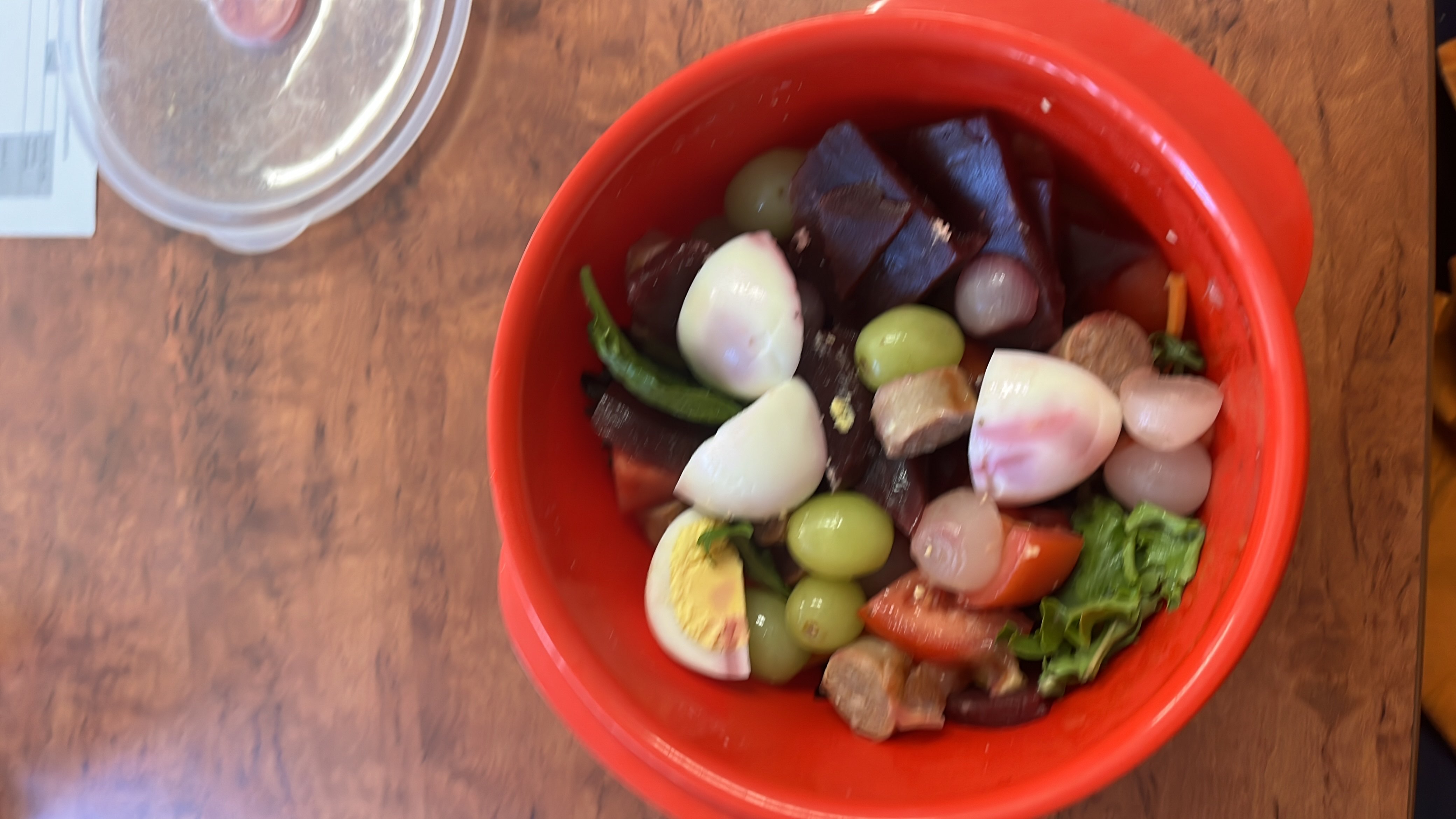 A healthy salad containing boiled eggs, grapes, beetroot, lettuce, onion, tomato, and green chili, providing a balanced mix of protein, carbs, and fats.