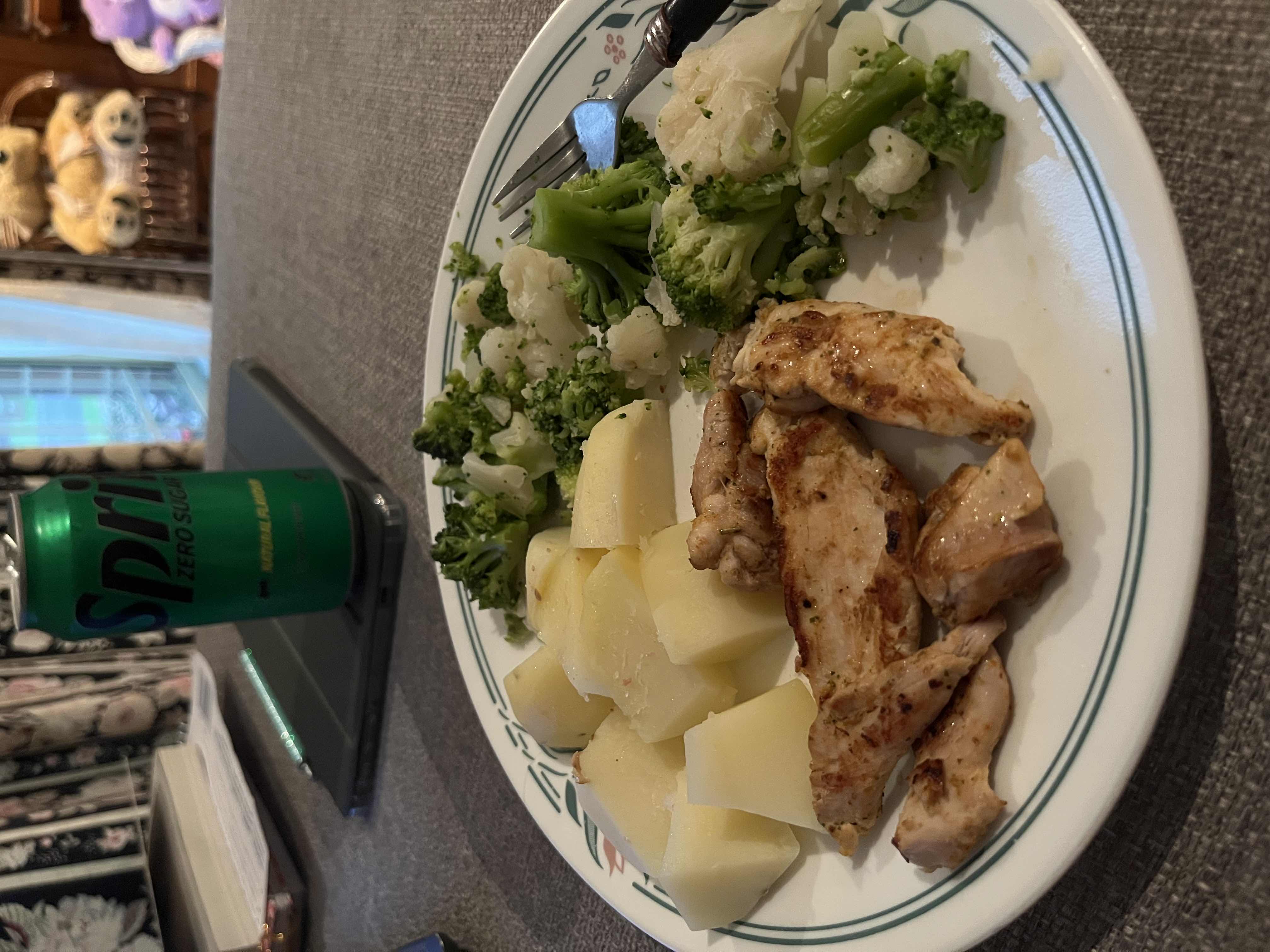 A balanced meal consisting of grilled chicken, boiled potatoes, steamed broccoli and cauliflower, accompanied by a can of Sprite Zero Sugar.