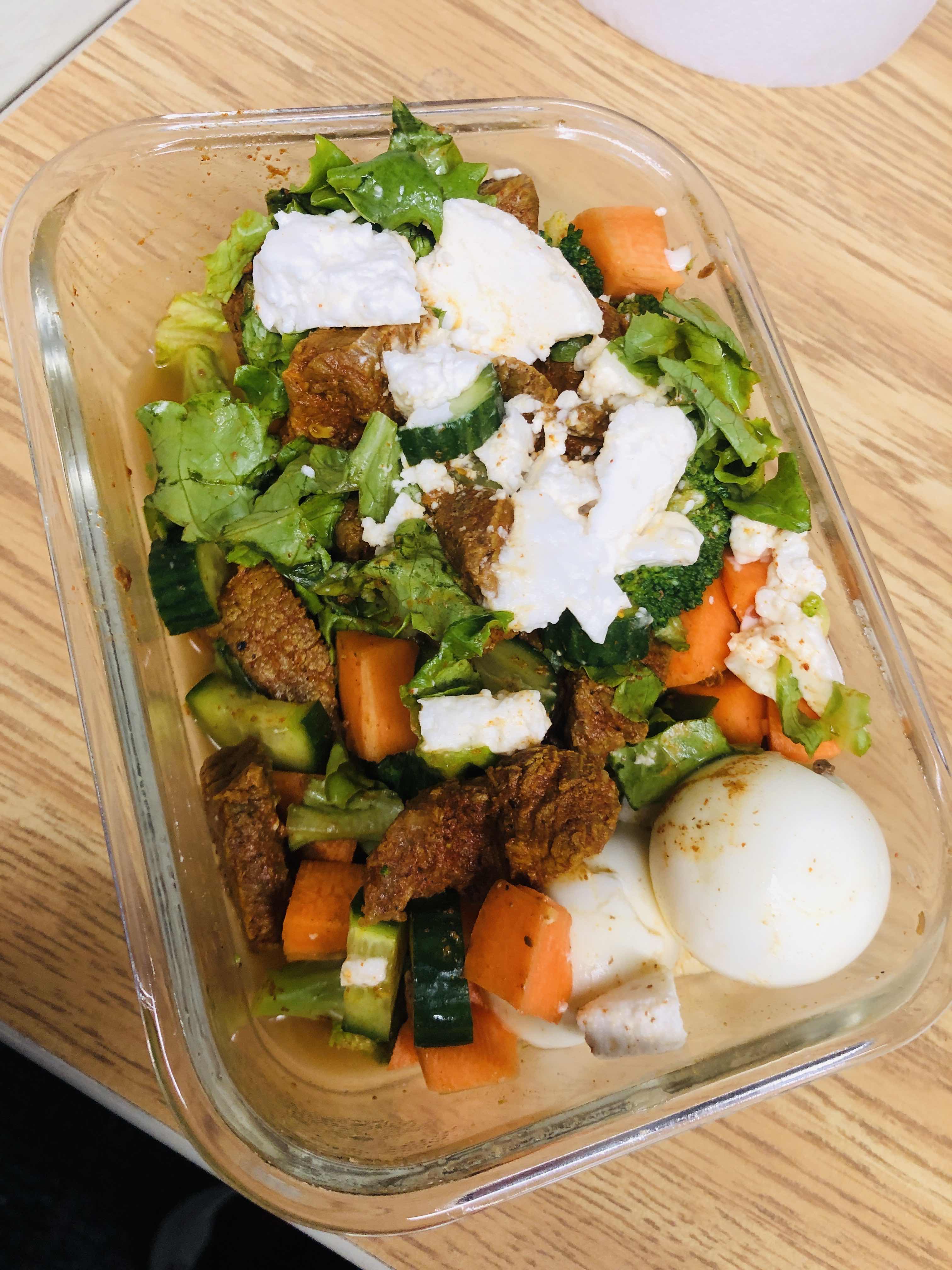A healthy salad containing lettuce, carrots, cucumbers, boiled egg, grilled meat, and cheese, providing a balanced mix of protein, carbs, and fats.