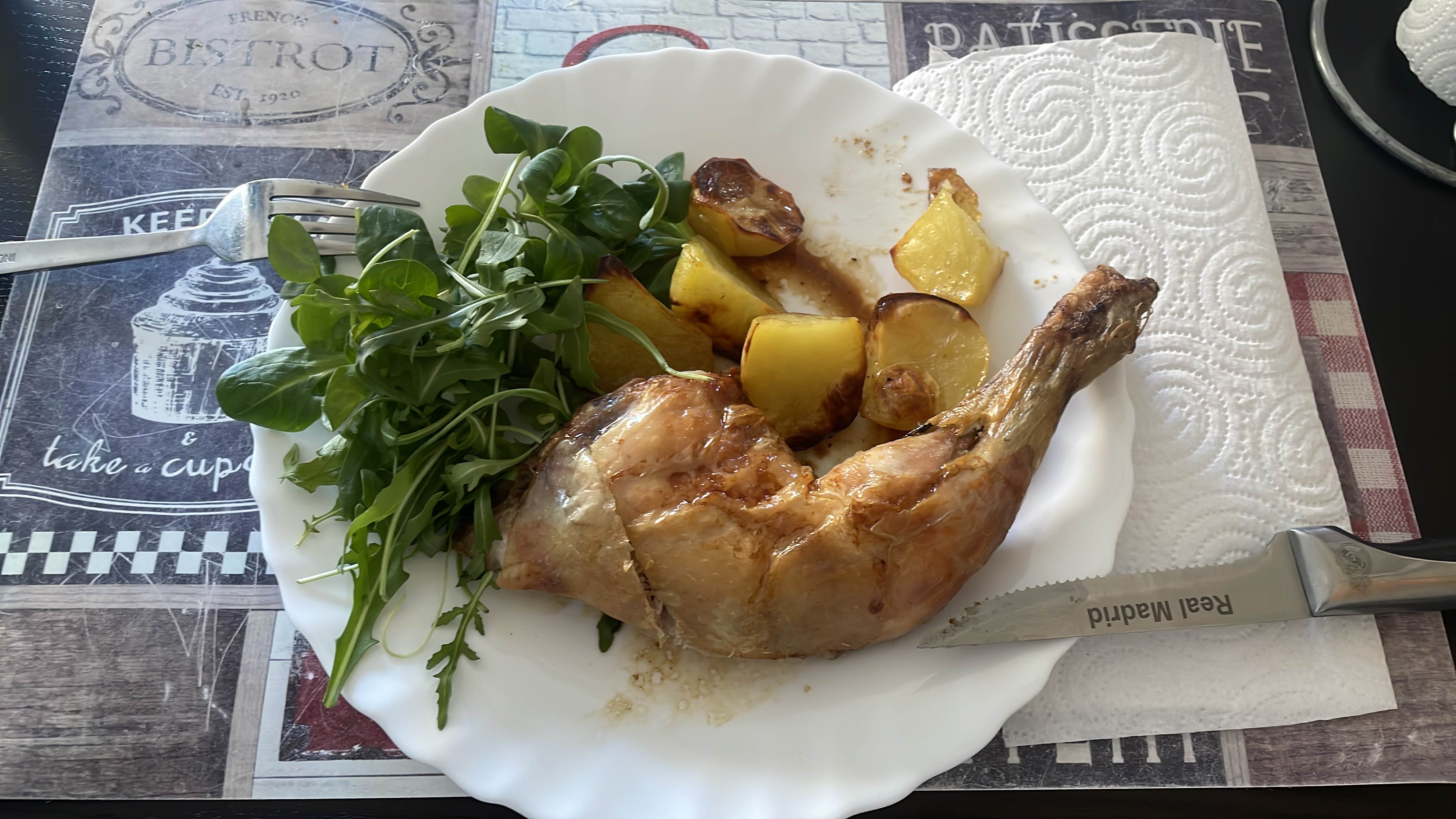 A balanced meal consisting of a roasted chicken leg, roasted potatoes, and fresh mixed greens.