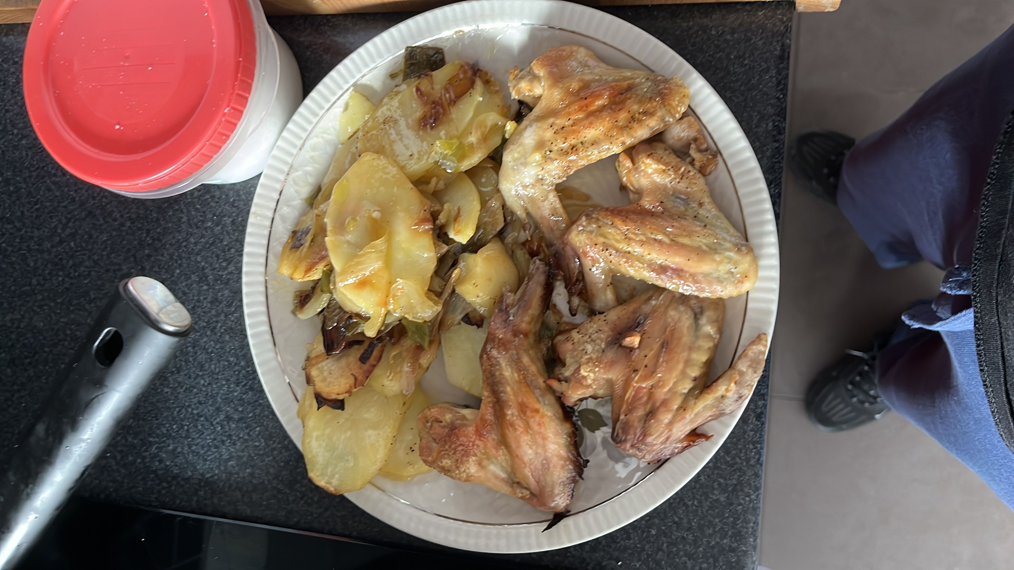 A plate of roasted chicken wings served with baked potatoes and vegetables, providing a balanced mix of protein, carbs, and fats.
