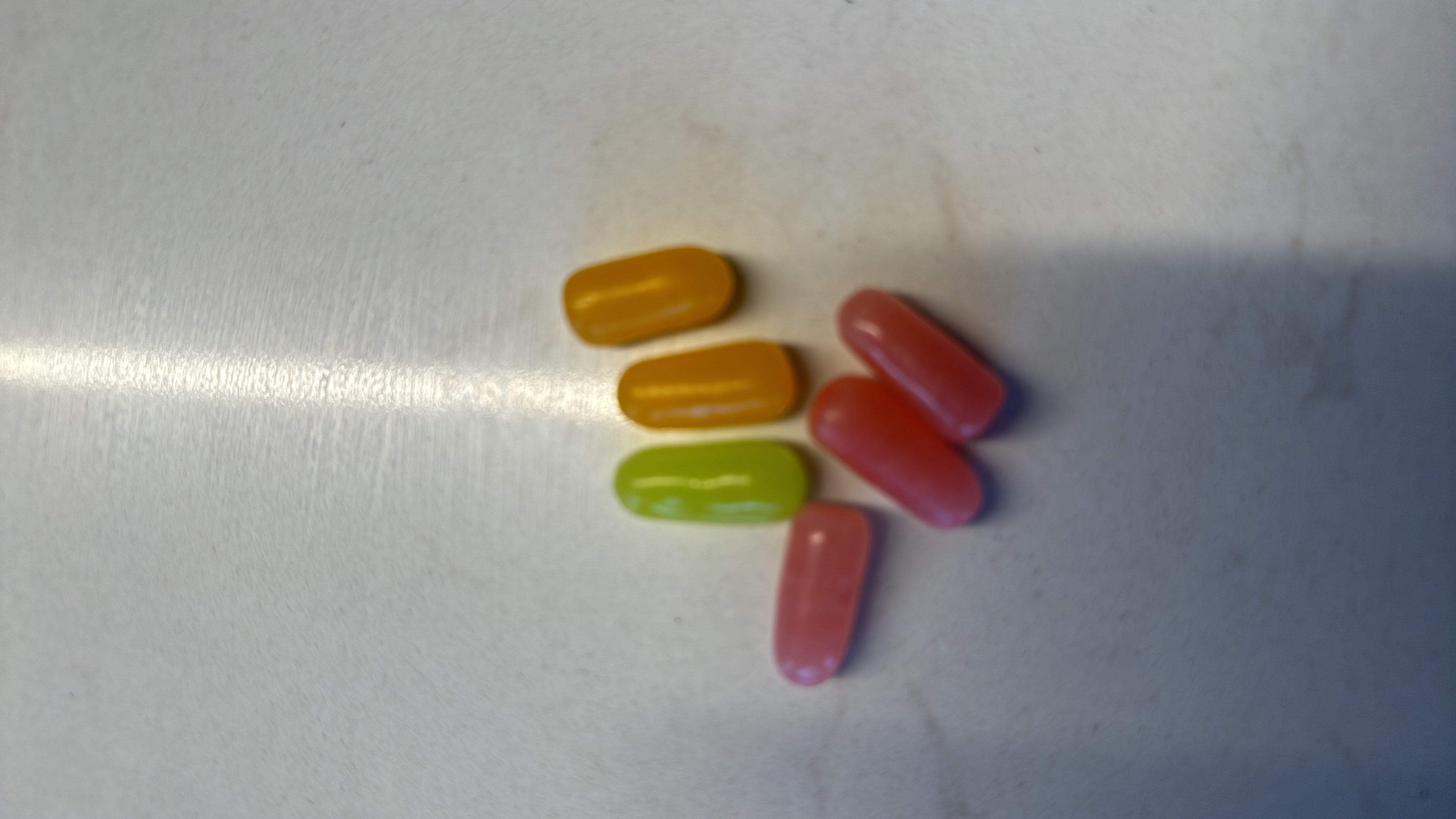 The image shows a collection of colorful tablets, likely multivitamins or supplements, which do not contain significant calories or macronutrients.