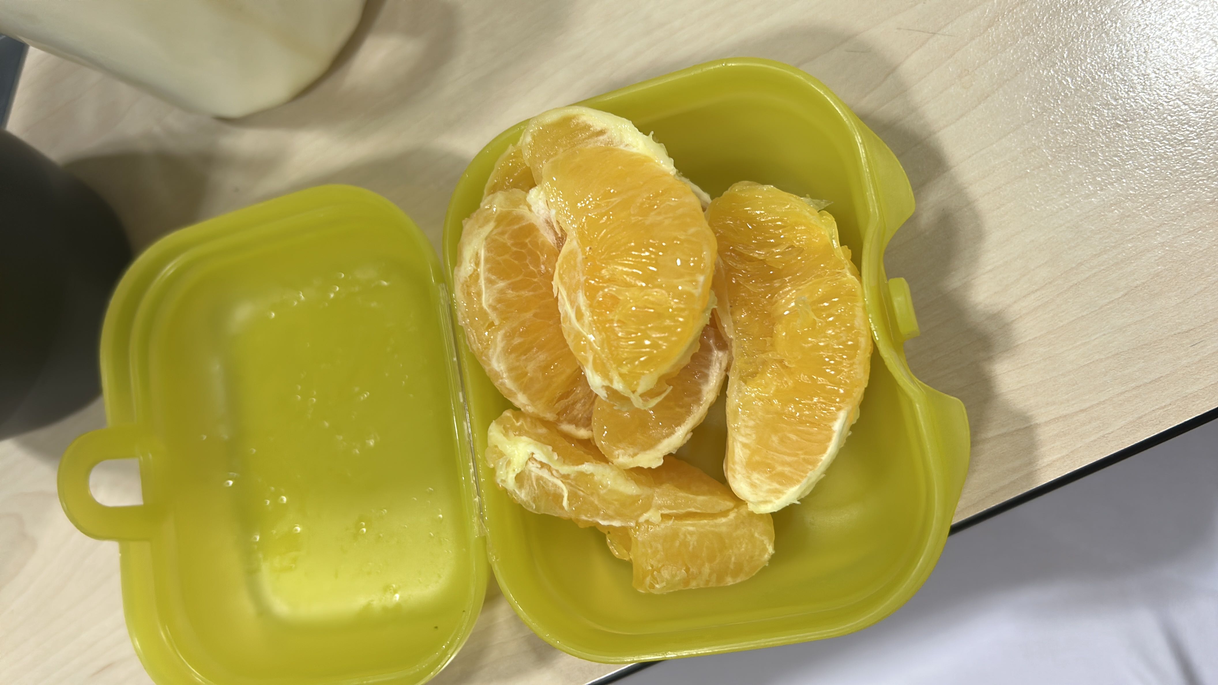 The image shows fresh orange slices in a container, which are a low-calorie, nutrient-rich snack.