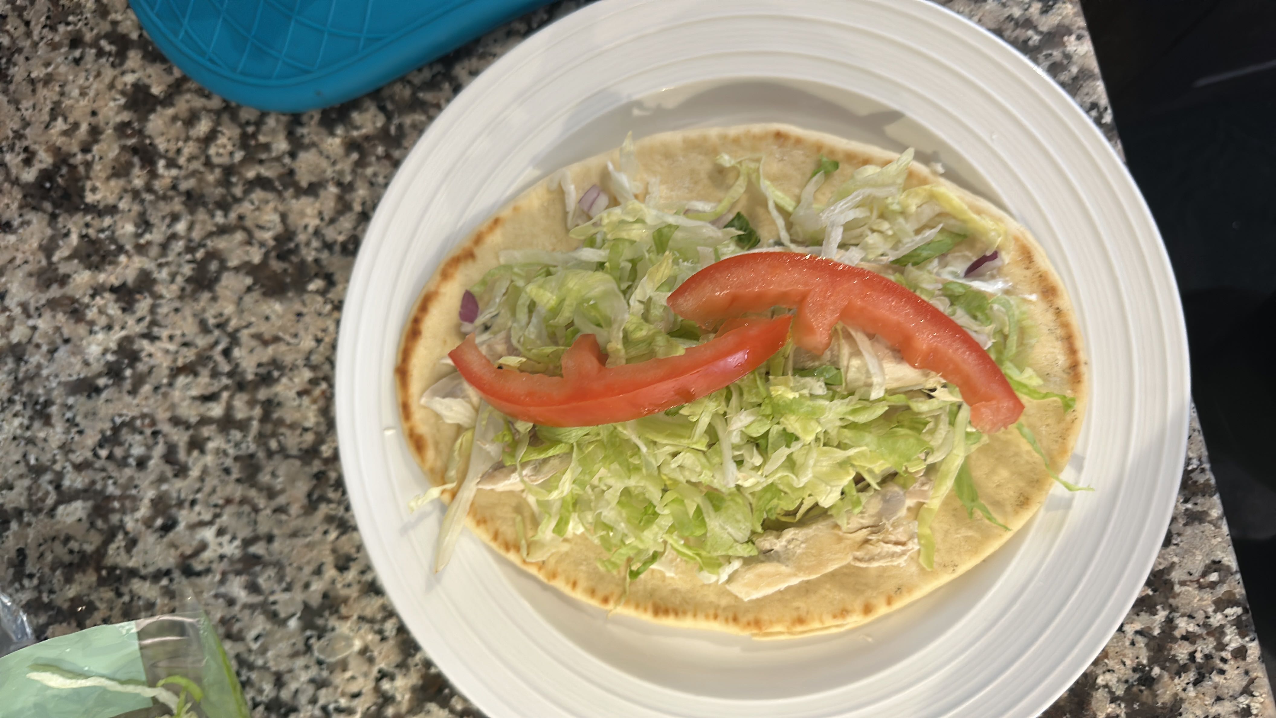 A flatbread wrap with chicken, lettuce, tomato, and dressing, offering a balanced mix of protein, carbs, and fats.