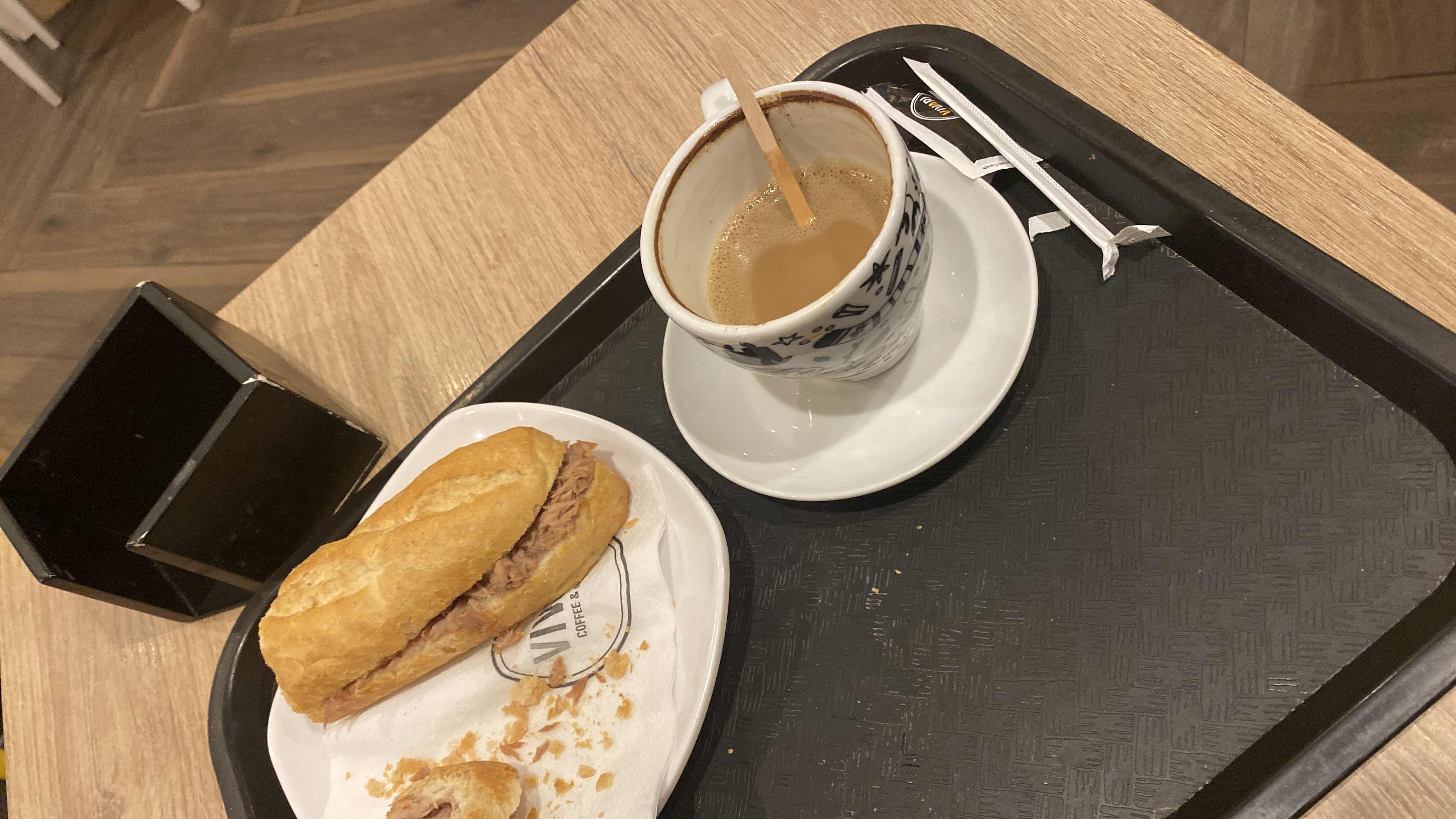 A meal consisting of a tuna sandwich and a cup of coffee, providing a balanced mix of protein, carbs, and fats.