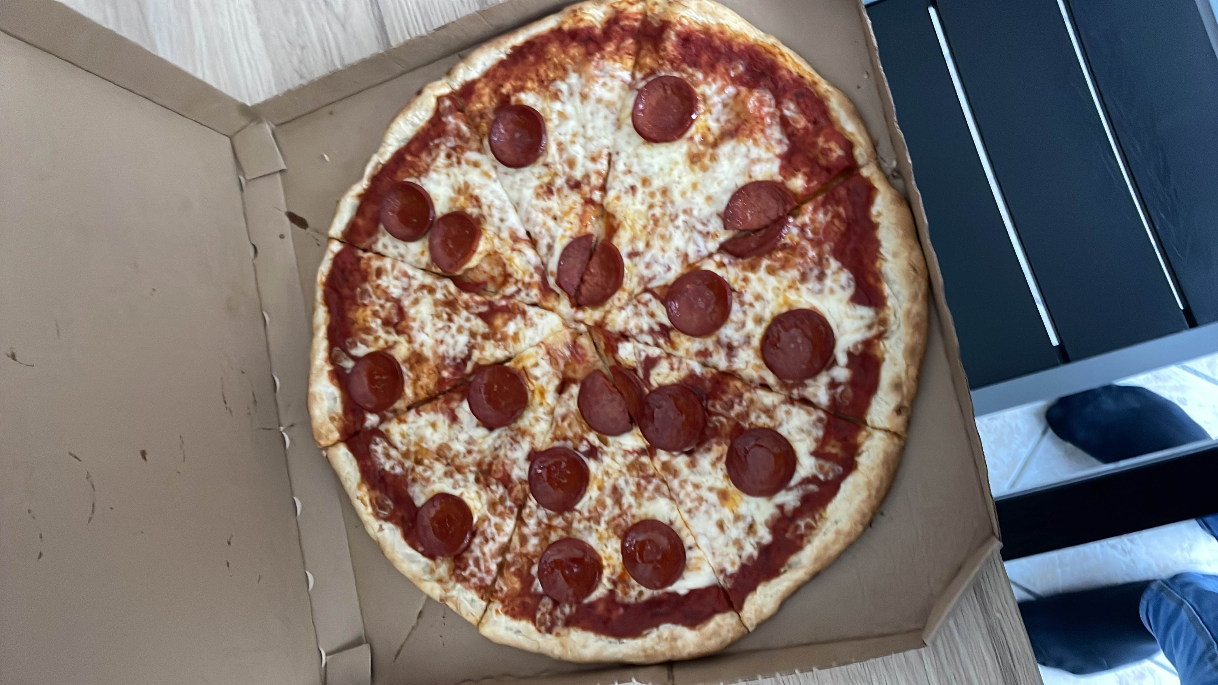 A chorizo pizza with cheese, tomato sauce, and a thin crust, divided into slices.