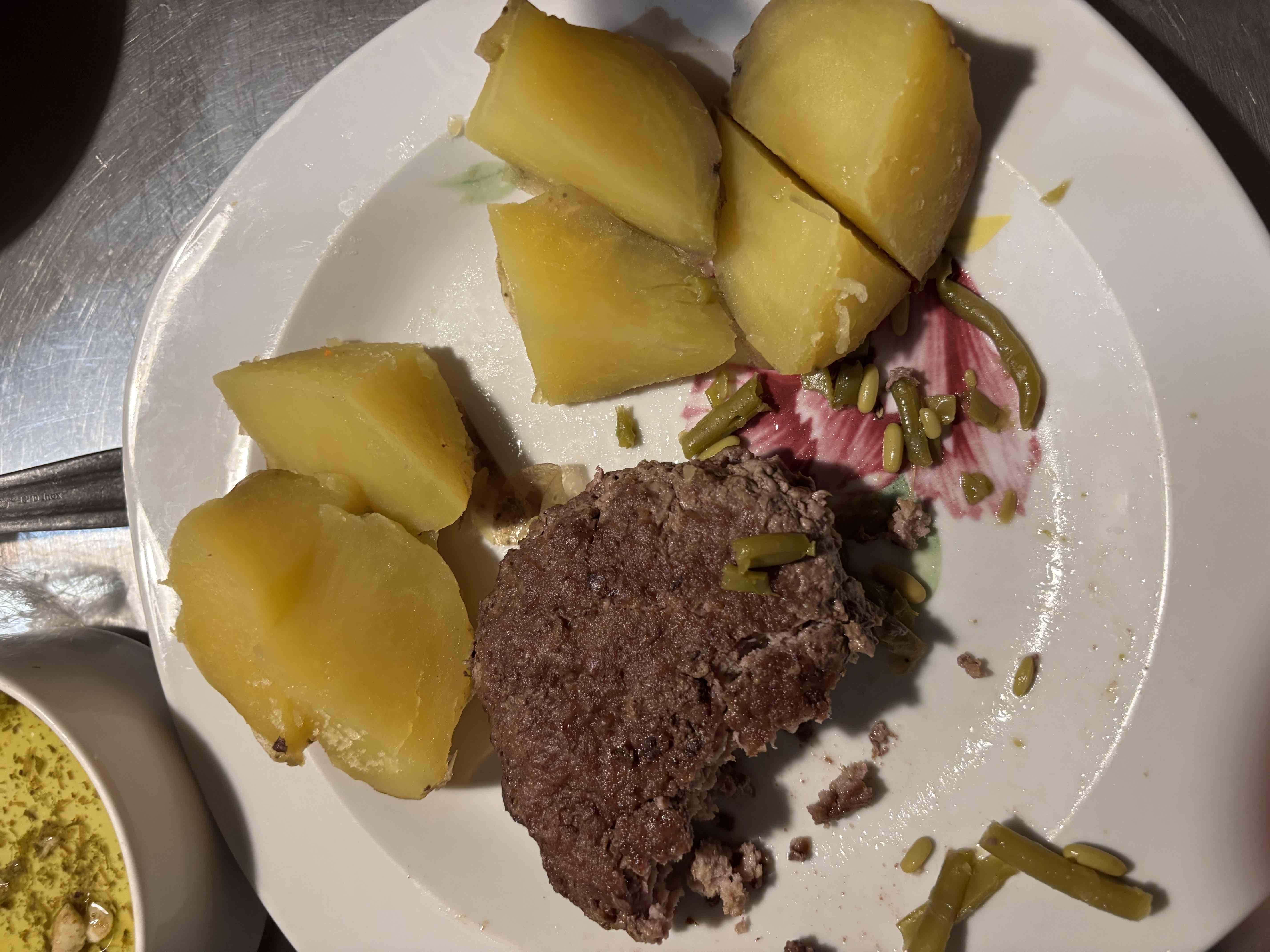 A meal consisting of boiled potatoes, a beef patty, and green beans, providing a balanced mix of protein, carbs, and fats.