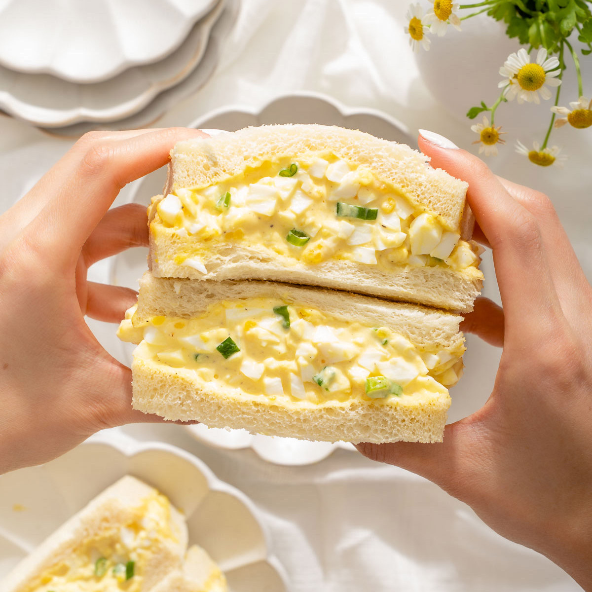 A high-protein egg salad sandwich made with eggs, light mayonnaise, and whole grain bread, garnished with green onions.