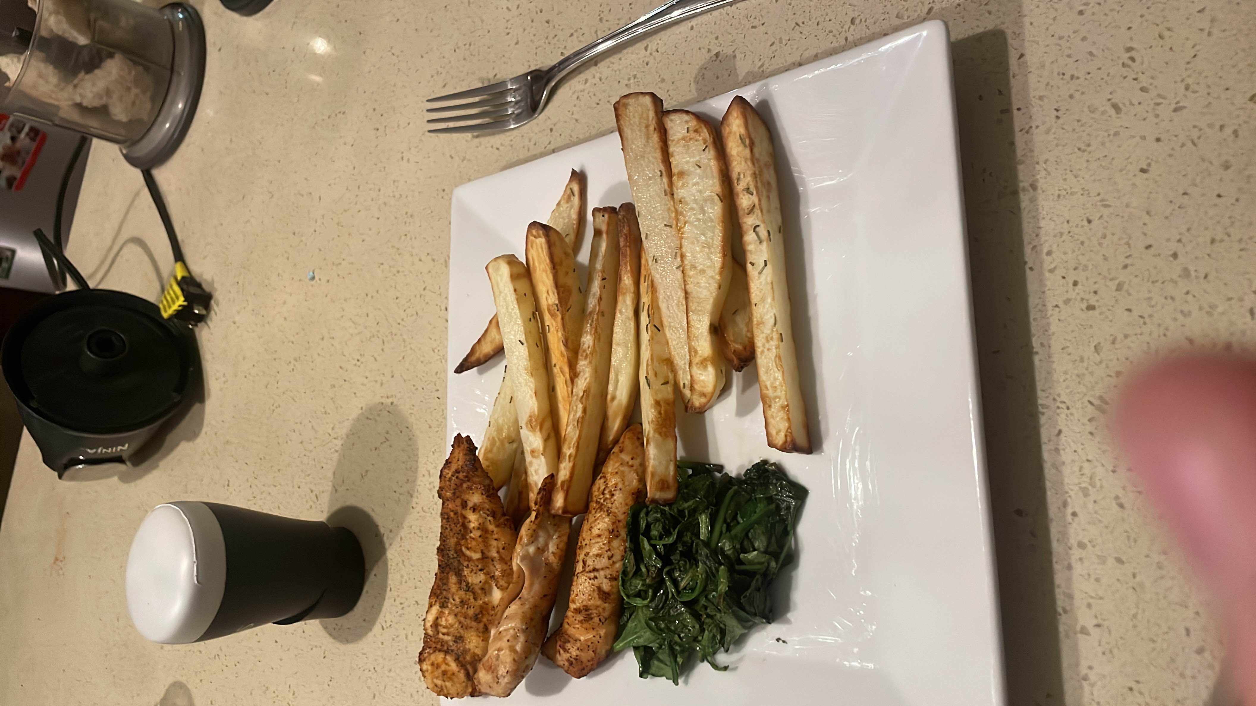A balanced meal consisting of seasoned chicken breast, baked parsnip fries, and sautéed spinach, providing a good mix of protein, carbs, and healthy fats.
