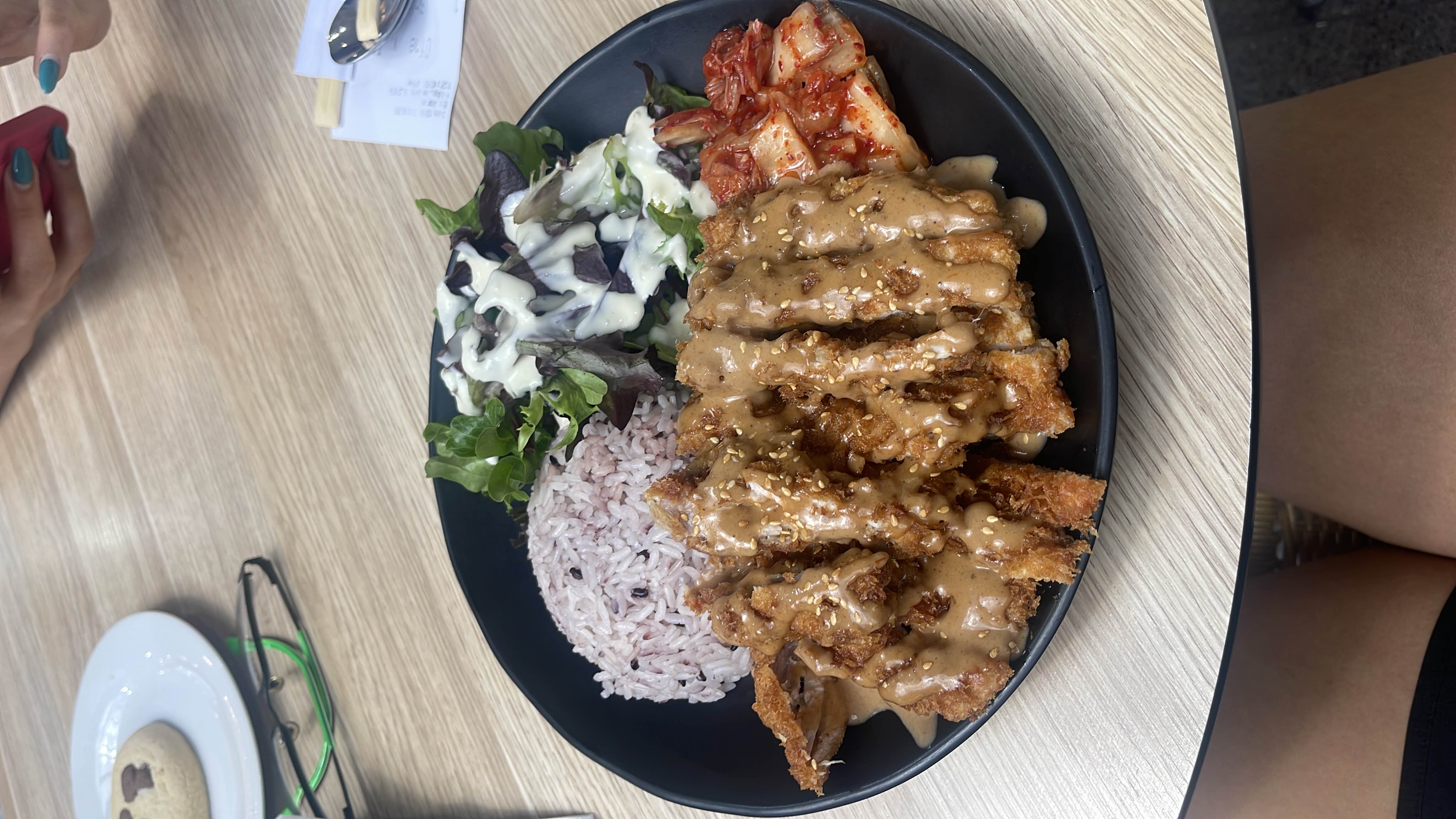 A balanced meal featuring fried chicken cutlet with sesame sauce, mixed grain rice, fresh salad with dressing, and a side of kimchi.