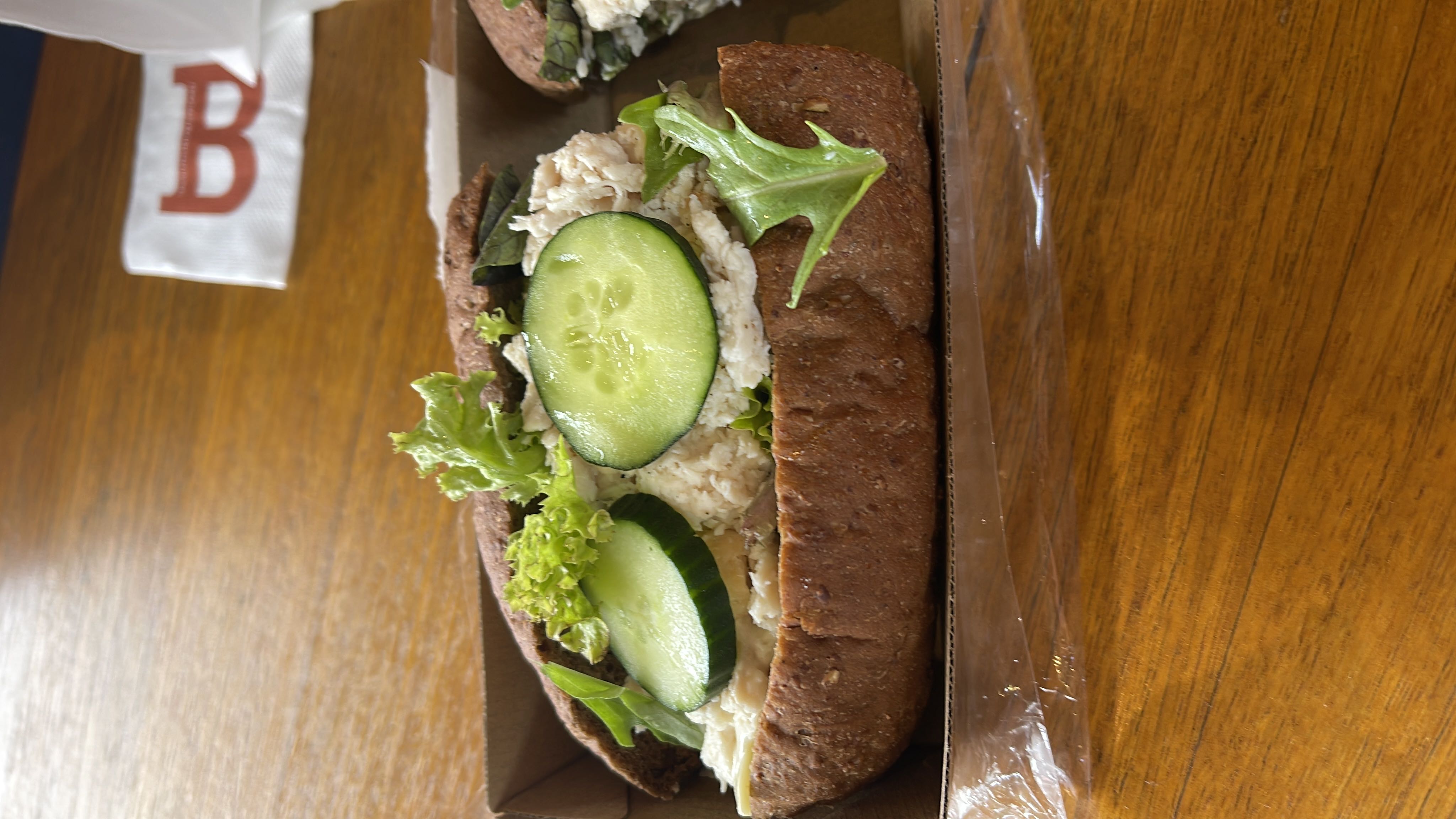 A healthy sandwich made with whole grain bread, chicken, cucumber, lettuce, and mayonnaise.