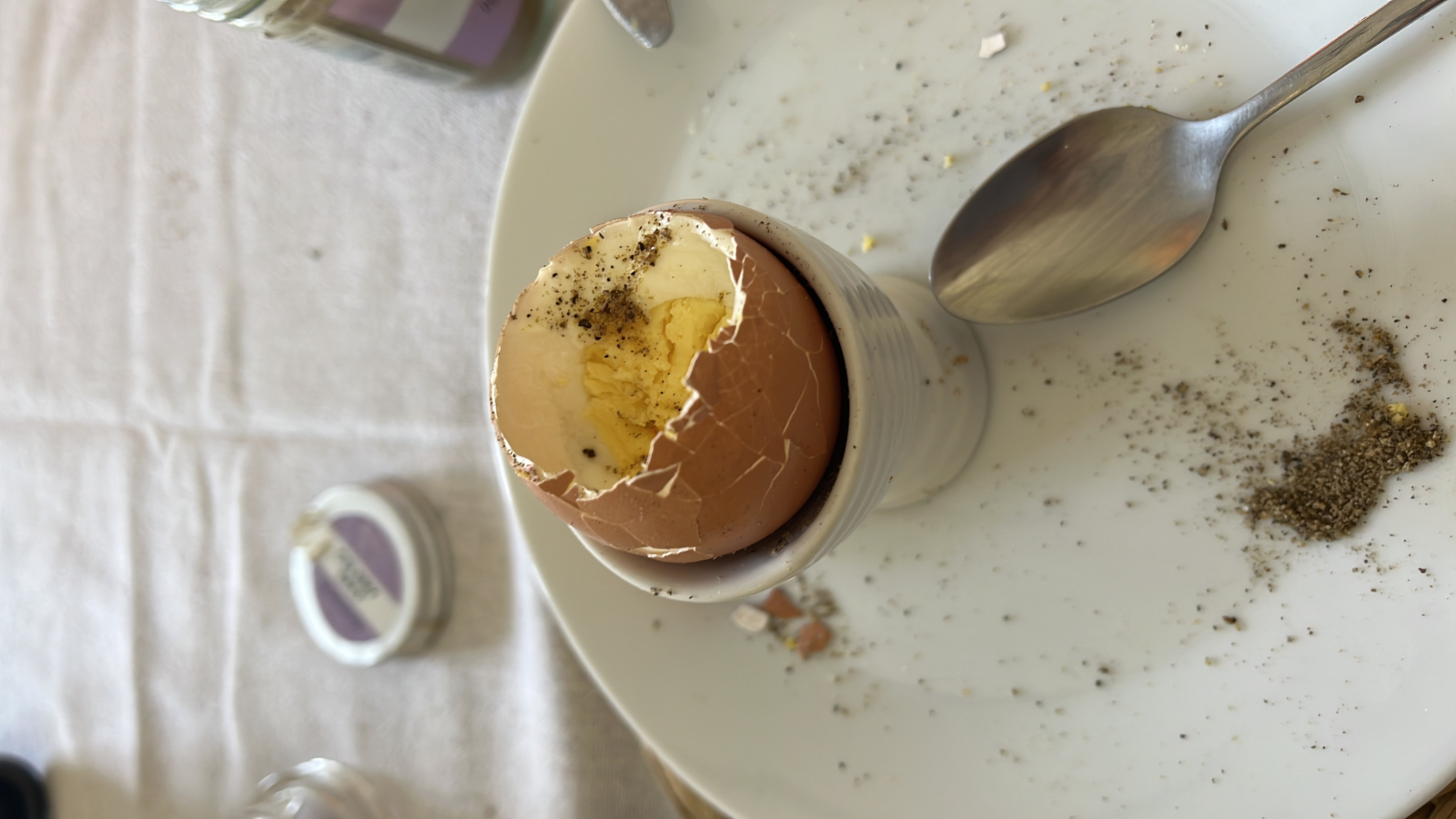A soft-boiled egg served in an egg cup, seasoned with black pepper.