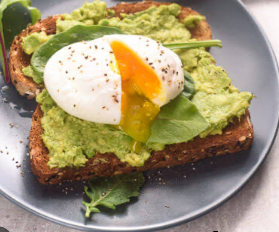 A nutritious dish featuring whole grain toast topped with mashed avocado, fresh greens, and a poached egg.