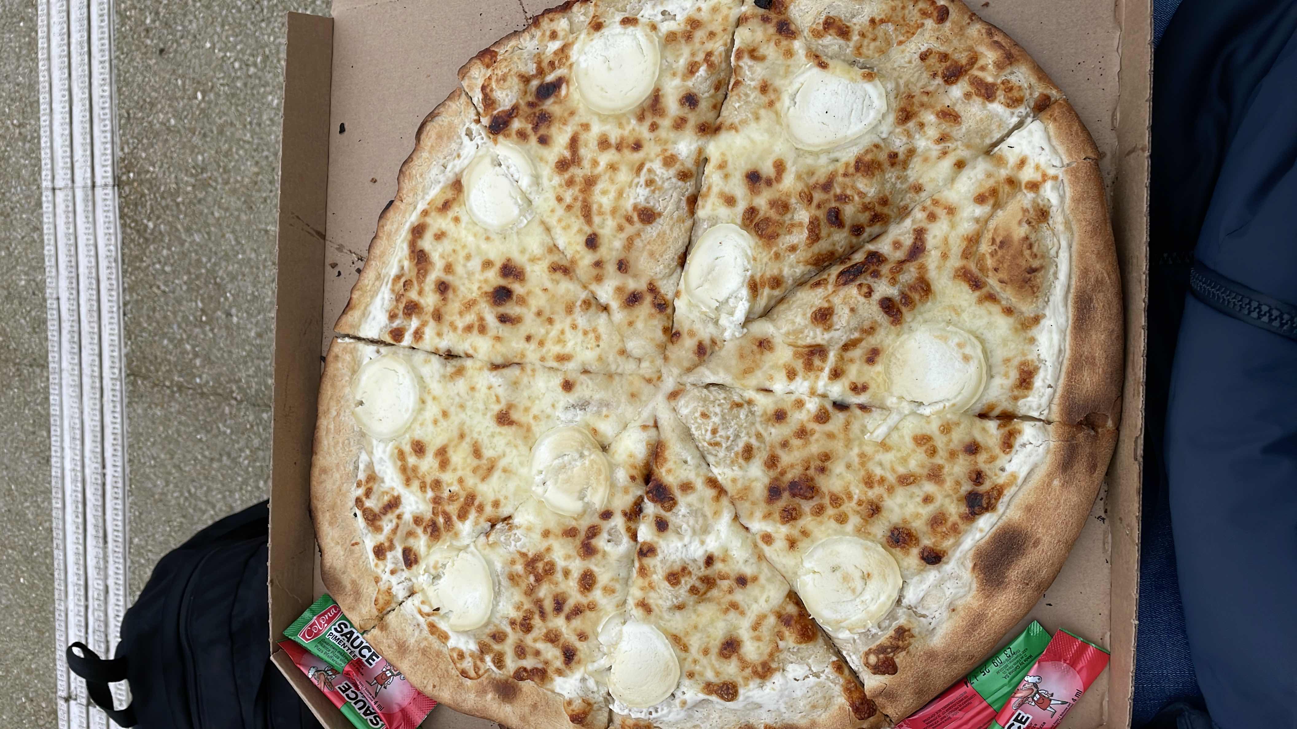 A cheese pizza with a creamy topping, featuring a crispy crust and individual cheese portions on each slice.