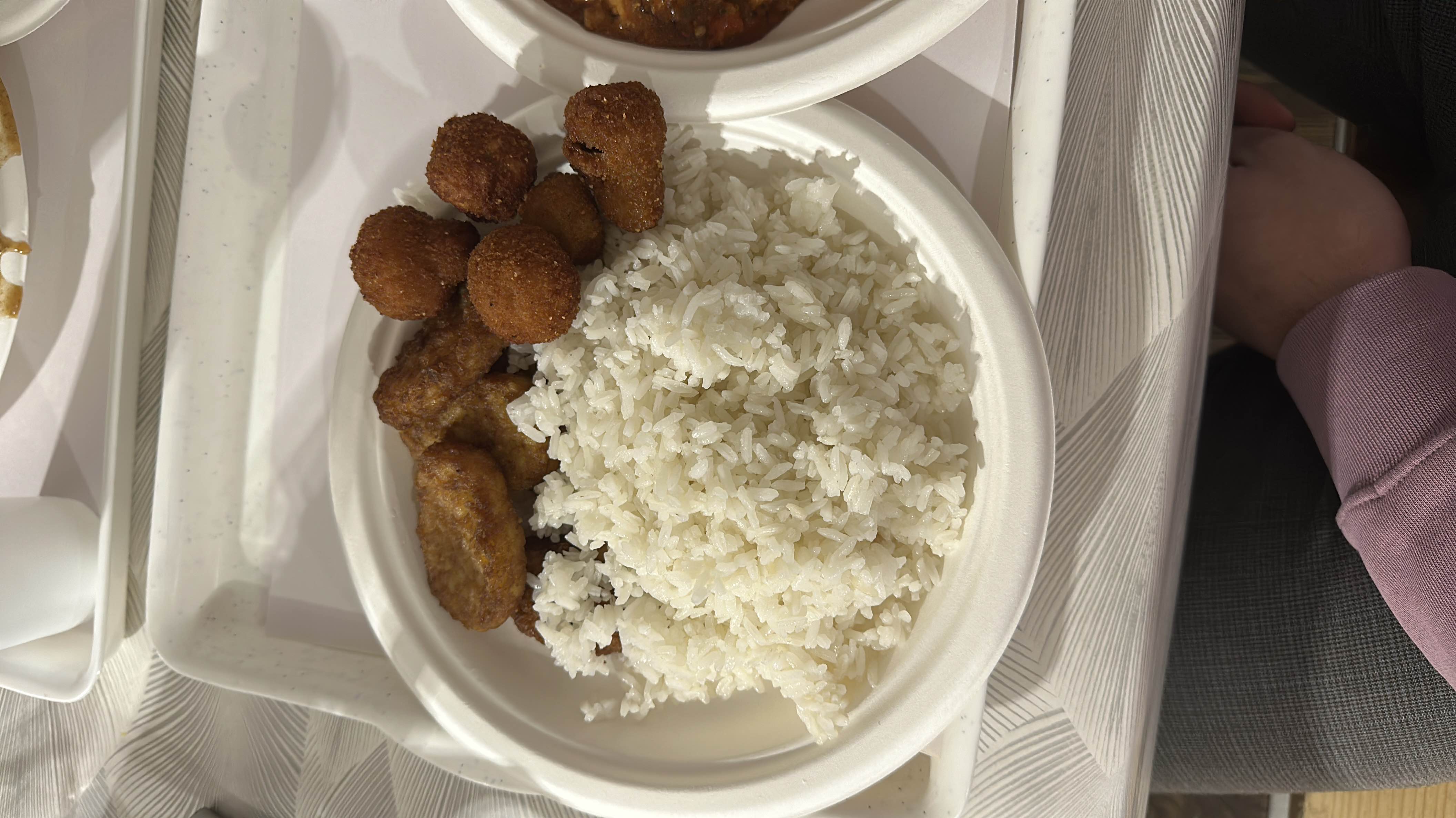 A meal consisting of white rice, fried chicken nuggets, and fried plantains, providing a balance of carbohydrates, protein, and fats.