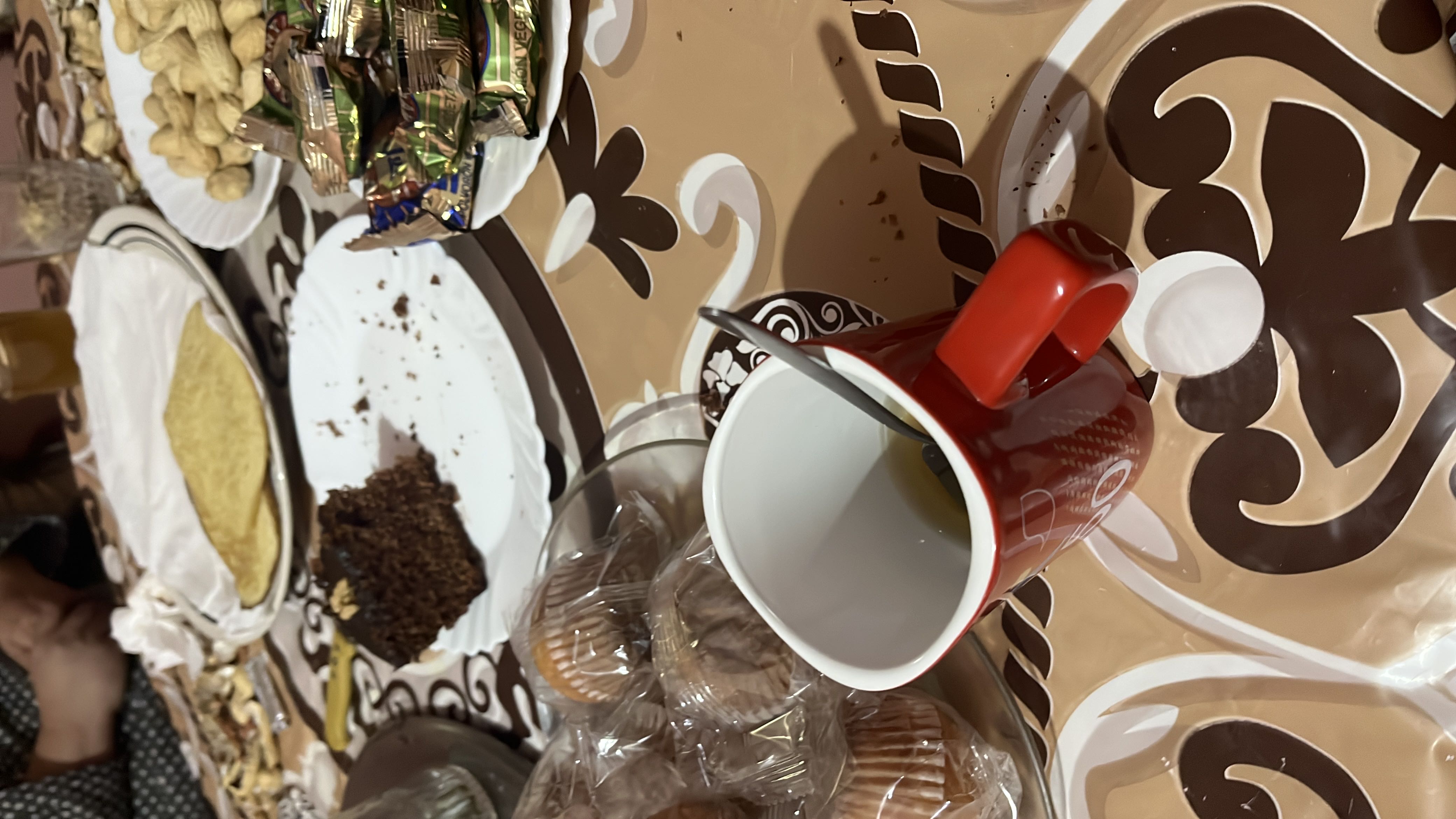 The image shows a table with various food items including chocolate cake, peanuts, muffins, and tea, providing a mix of carbs, fats, and protein.