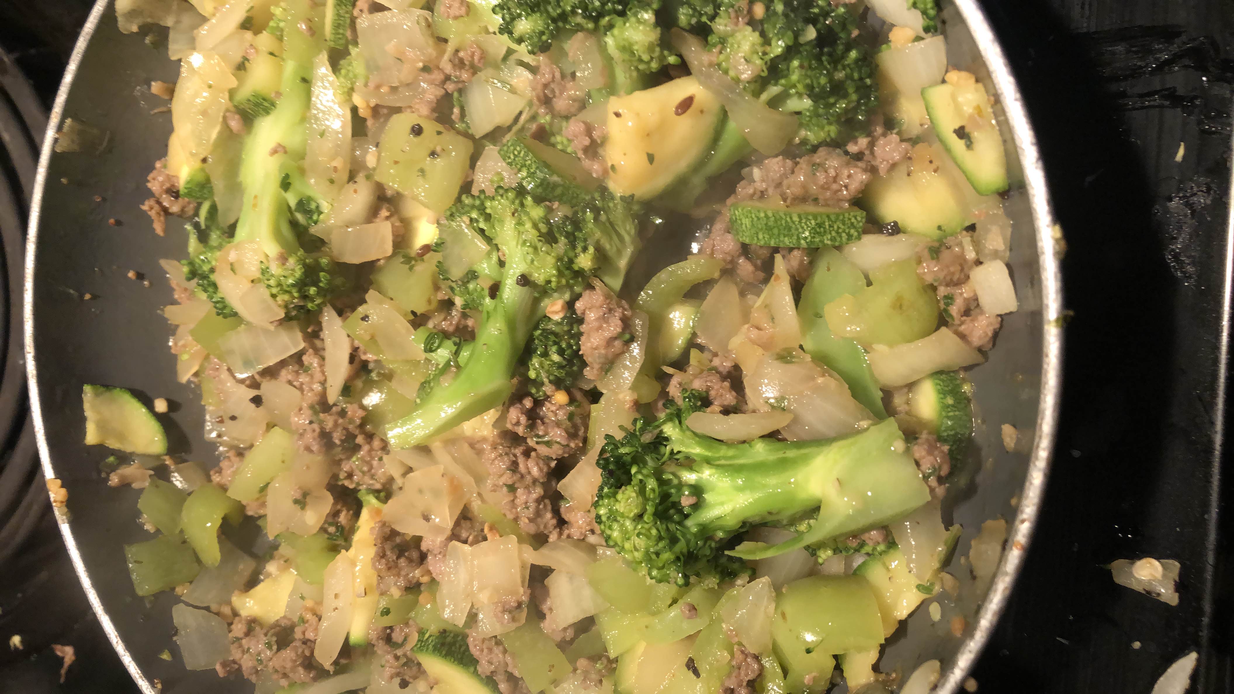 A healthy stir-fry dish featuring broccoli, ground beef, zucchini, onion, and bell pepper, providing a balanced mix of protein, carbs, and fats.