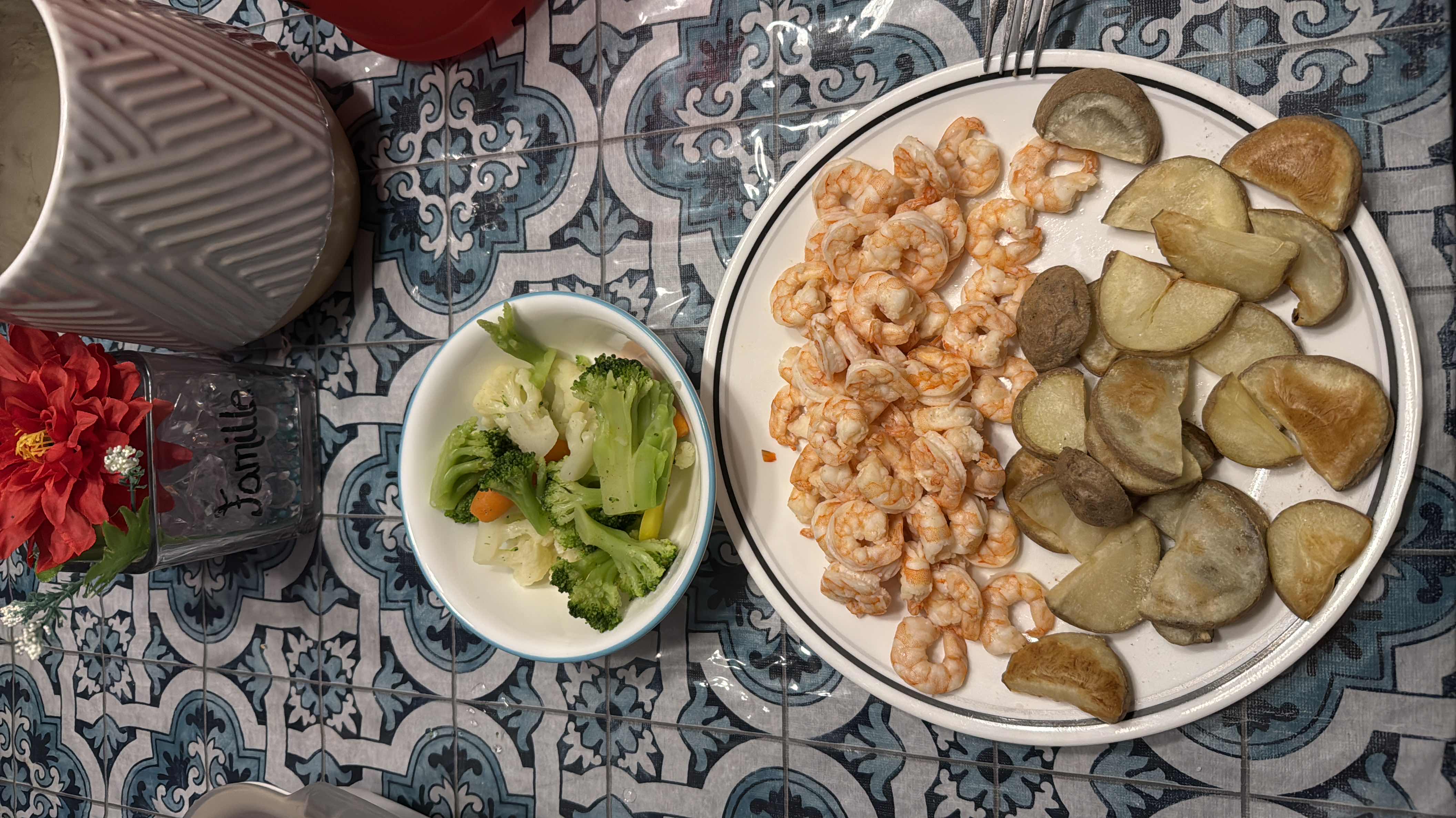 A balanced meal consisting of shrimp, roasted potatoes, and steamed vegetables, providing a good mix of protein, carbs, and minimal fats.
