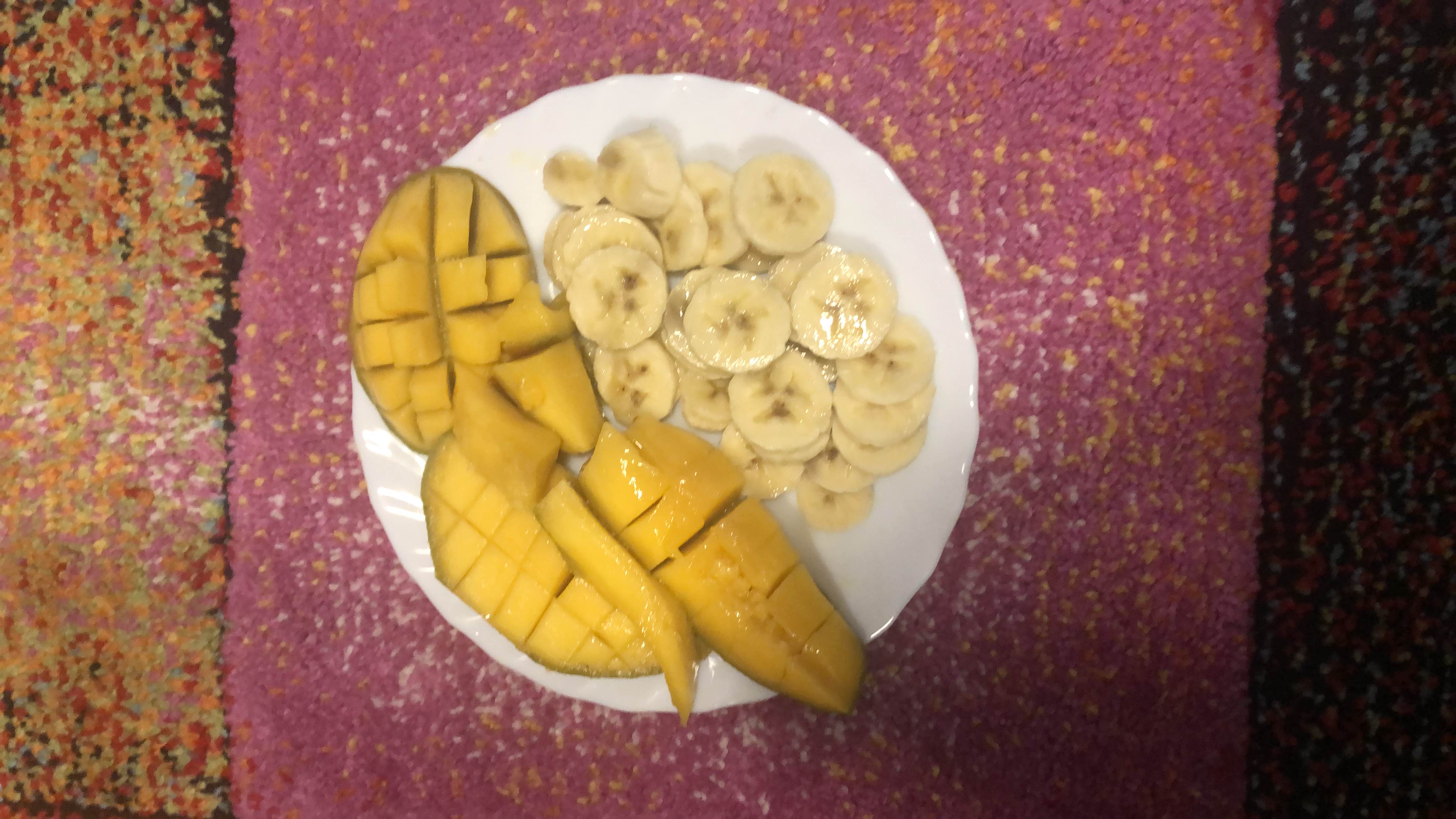 A plate of fresh mango and banana slices, providing a healthy and nutrient-rich snack.