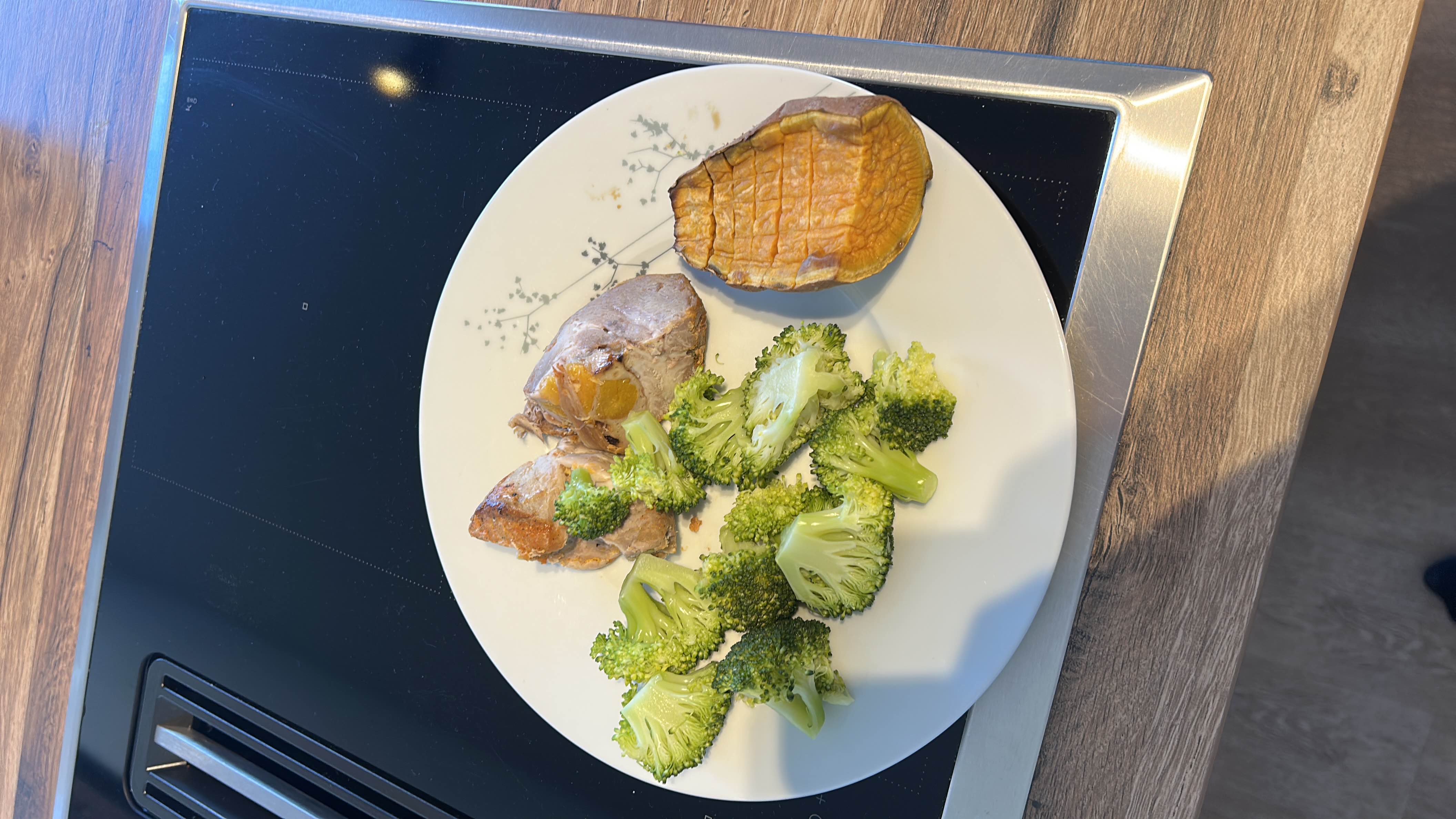 A balanced meal consisting of roasted chicken, steamed broccoli, and baked sweet potato, providing a good mix of protein, carbs, and fats.