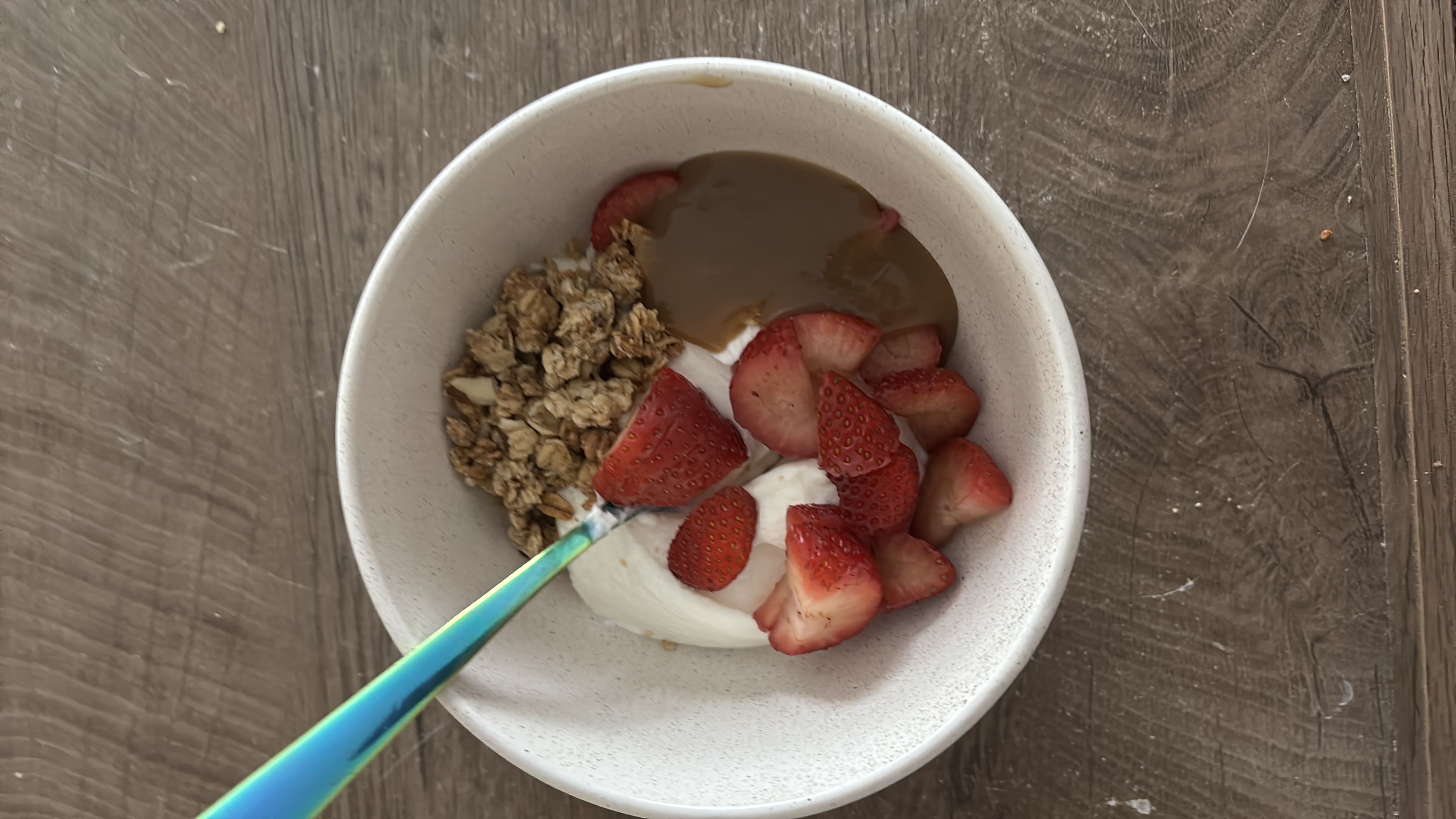 A nutritious bowl containing Greek yogurt, fresh strawberries, granola, and peanut butter, offering a balanced mix of protein, carbs, and fats.
