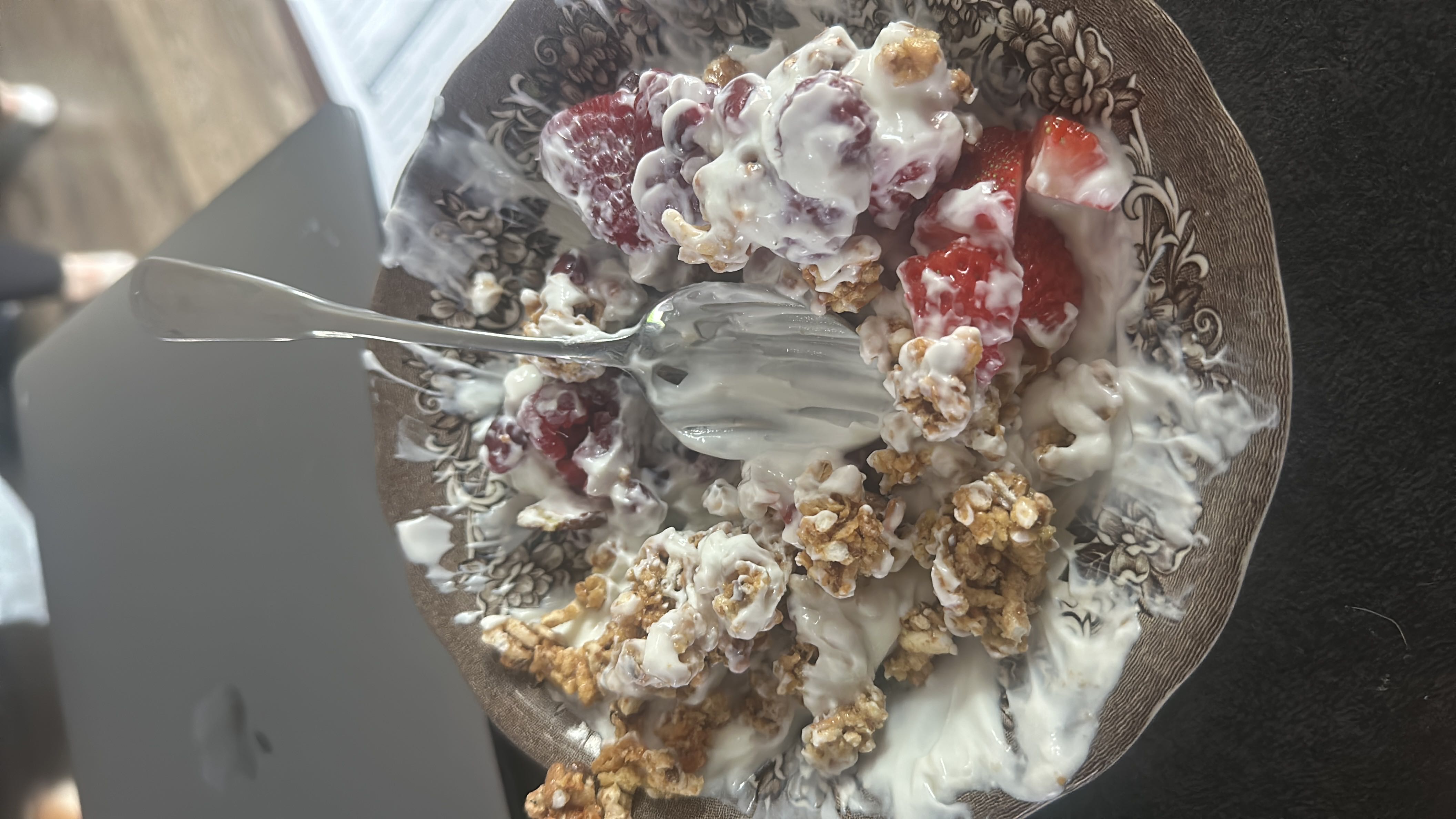 A bowl of yogurt mixed with granola and fresh strawberries, providing a balanced mix of protein, carbs, and fats.