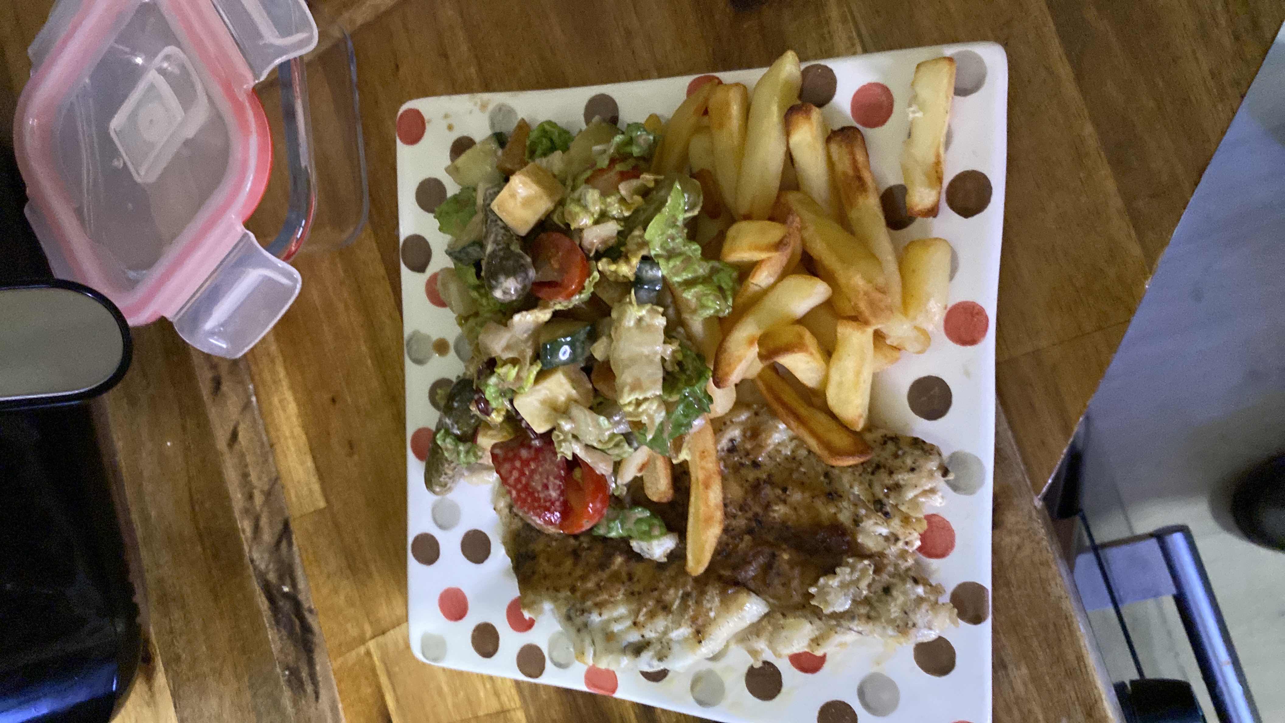 A balanced meal consisting of grilled fish, a fresh salad with mixed vegetables, and a side of French fries.
