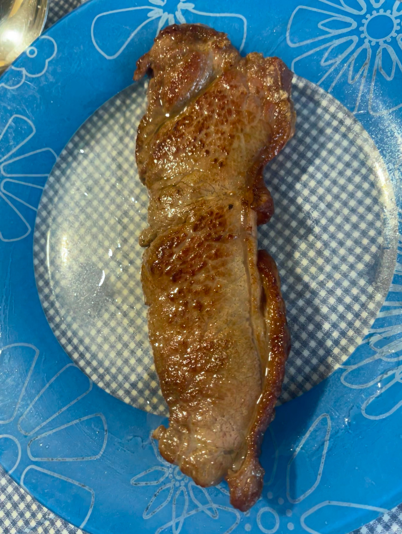 A cooked beef steak served on a blue plate, rich in protein and fats with no carbohydrates.