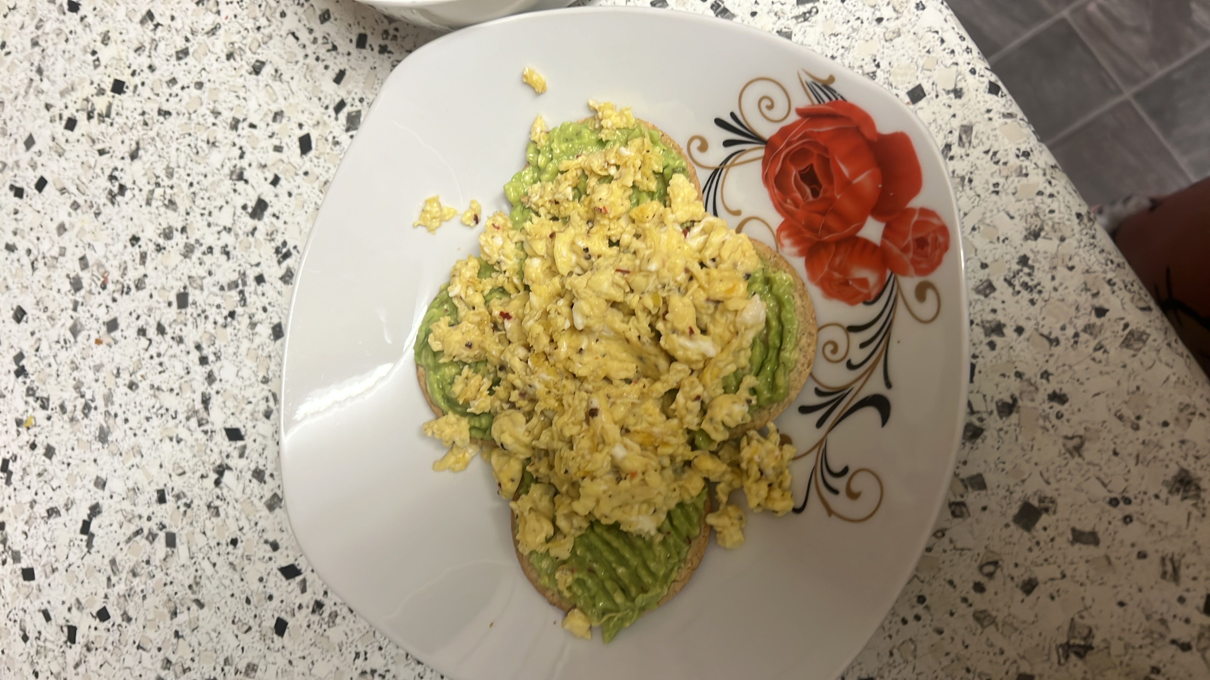 A plate of avocado toast topped with scrambled eggs, providing a balanced mix of healthy fats, protein, and carbohydrates.