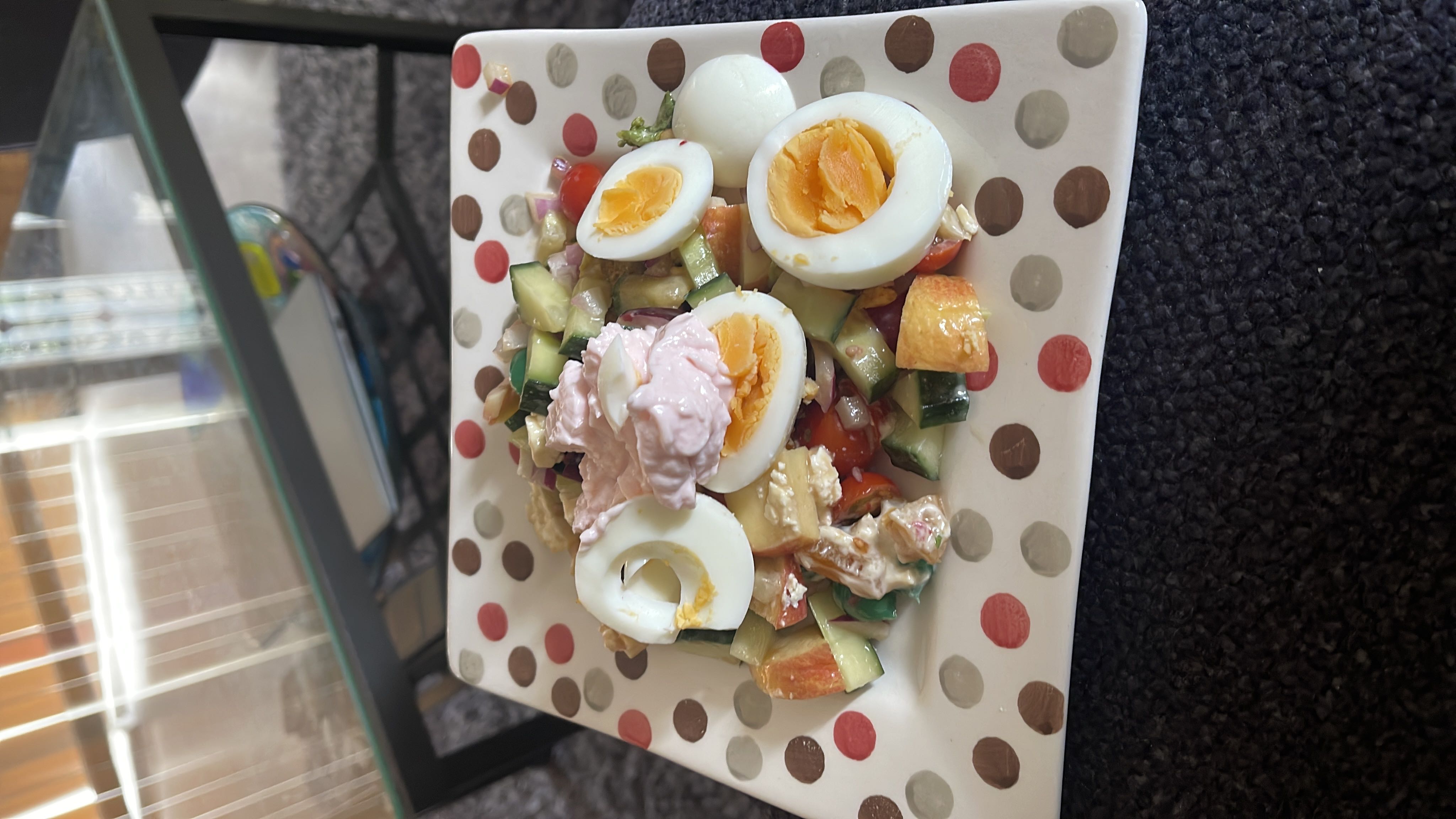 A healthy salad with boiled eggs, fresh vegetables, peach slices, and a yogurt-based dressing.