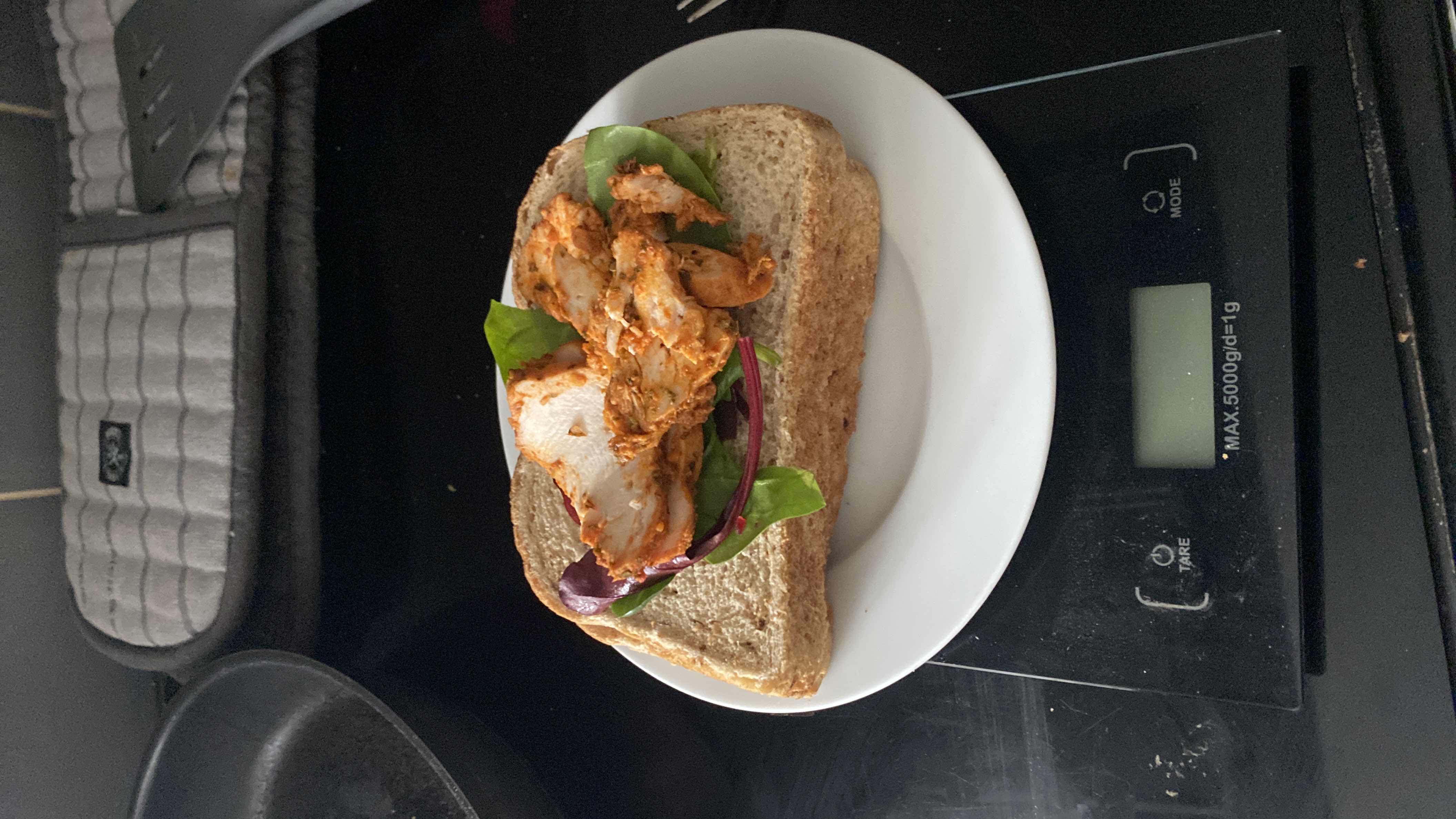 A healthy sandwich made with whole grain bread, grilled chicken, and mixed greens, providing a balanced mix of protein, carbs, and fats.