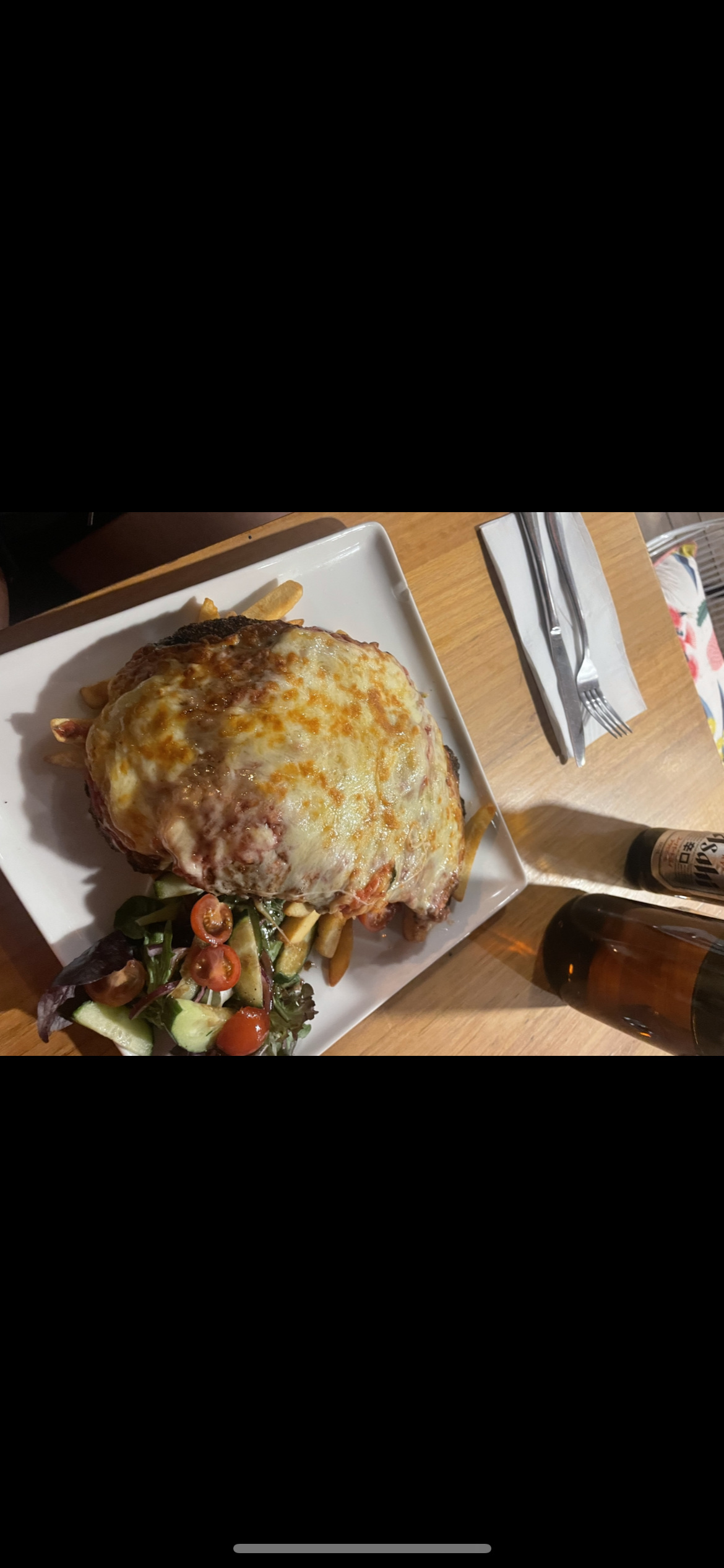 A hearty meal consisting of a chicken schnitzel topped with melted cheese, served with fries and a side salad.