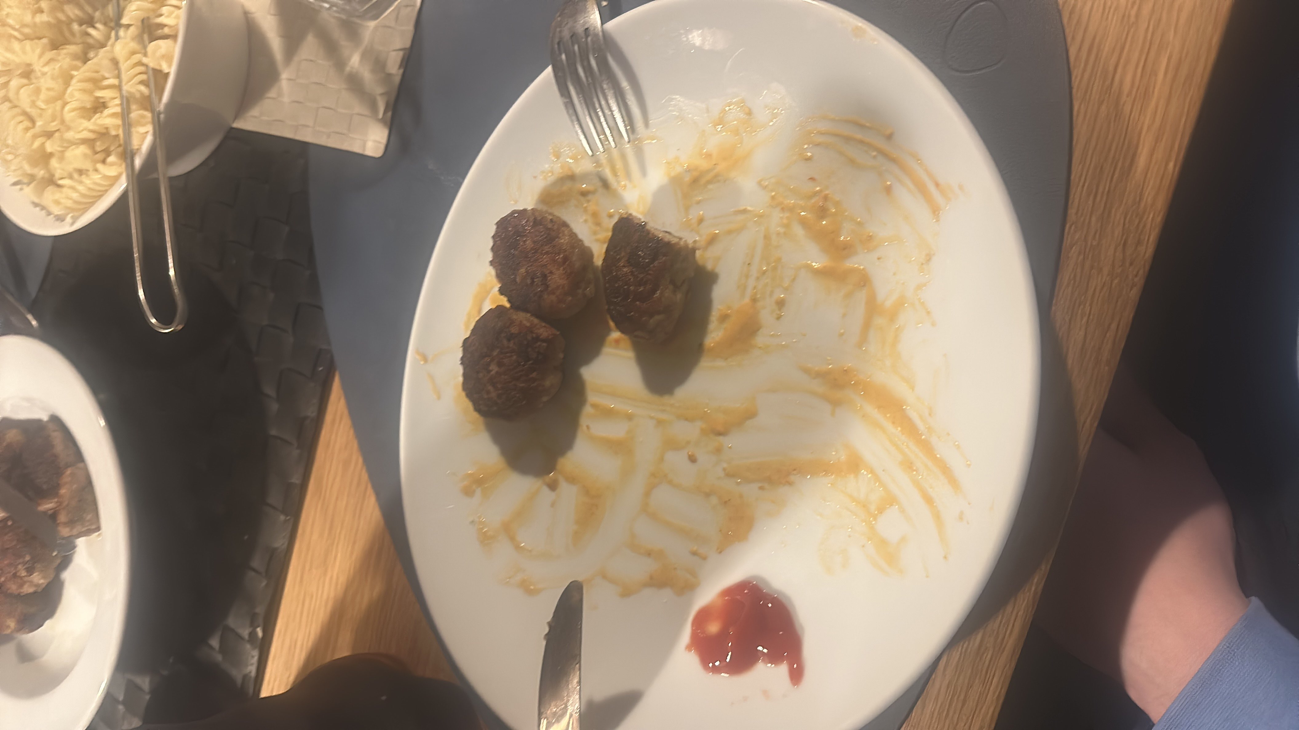 The image shows a plate with three meatballs, a small portion of ketchup, and remnants of pasta, suggesting a meal with moderate calories and a balanced macronutrient profile.