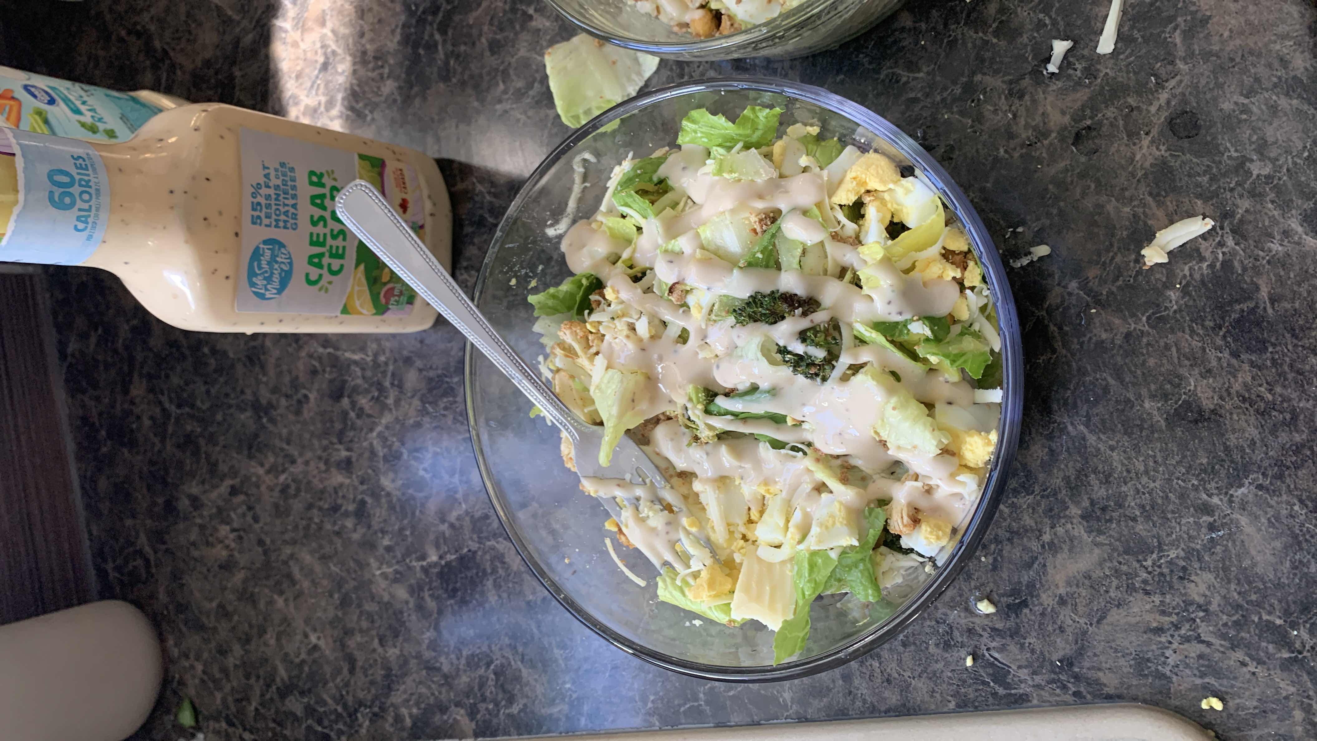 A Caesar salad with lettuce, boiled egg, broccoli, croutons, and Caesar dressing, providing a balanced mix of protein, carbs, and fats.