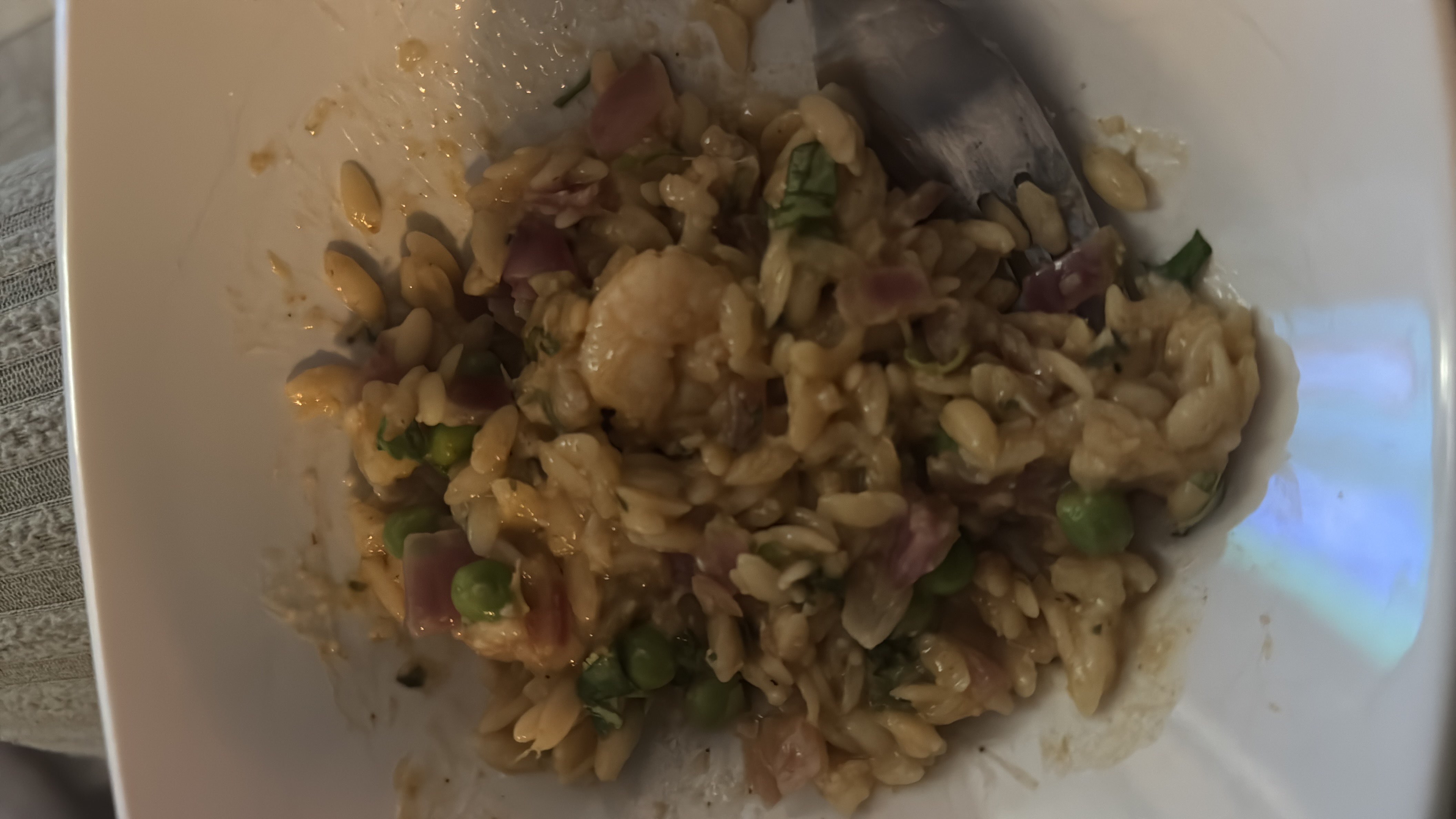 A dish consisting of orzo pasta, shrimp, peas, onions, and herbs, providing a balanced mix of protein, carbs, and fats.