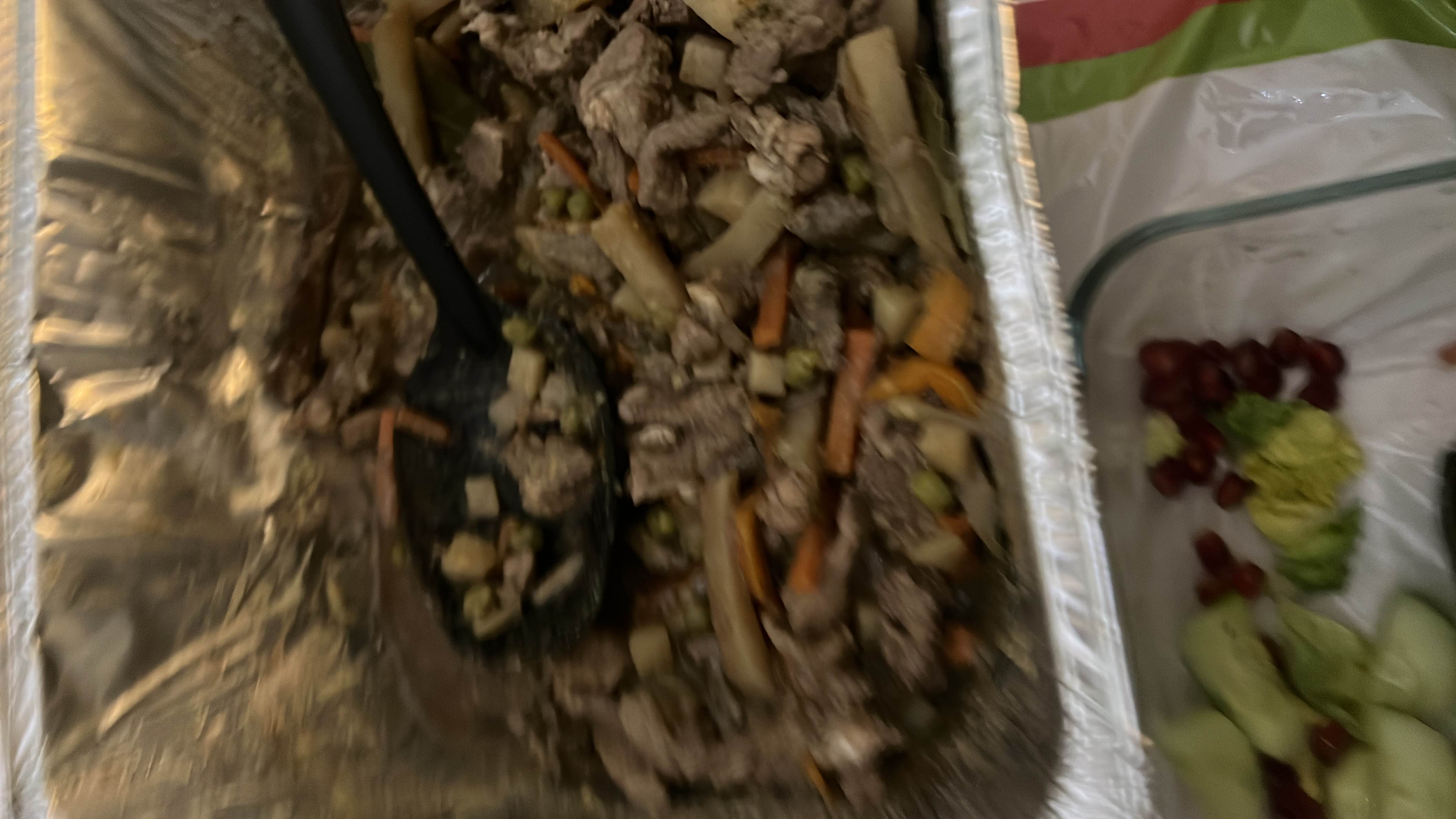 A mixed dish containing beef strips, vegetables like carrots, peas, and potatoes, served with cucumber slices and garnishes.