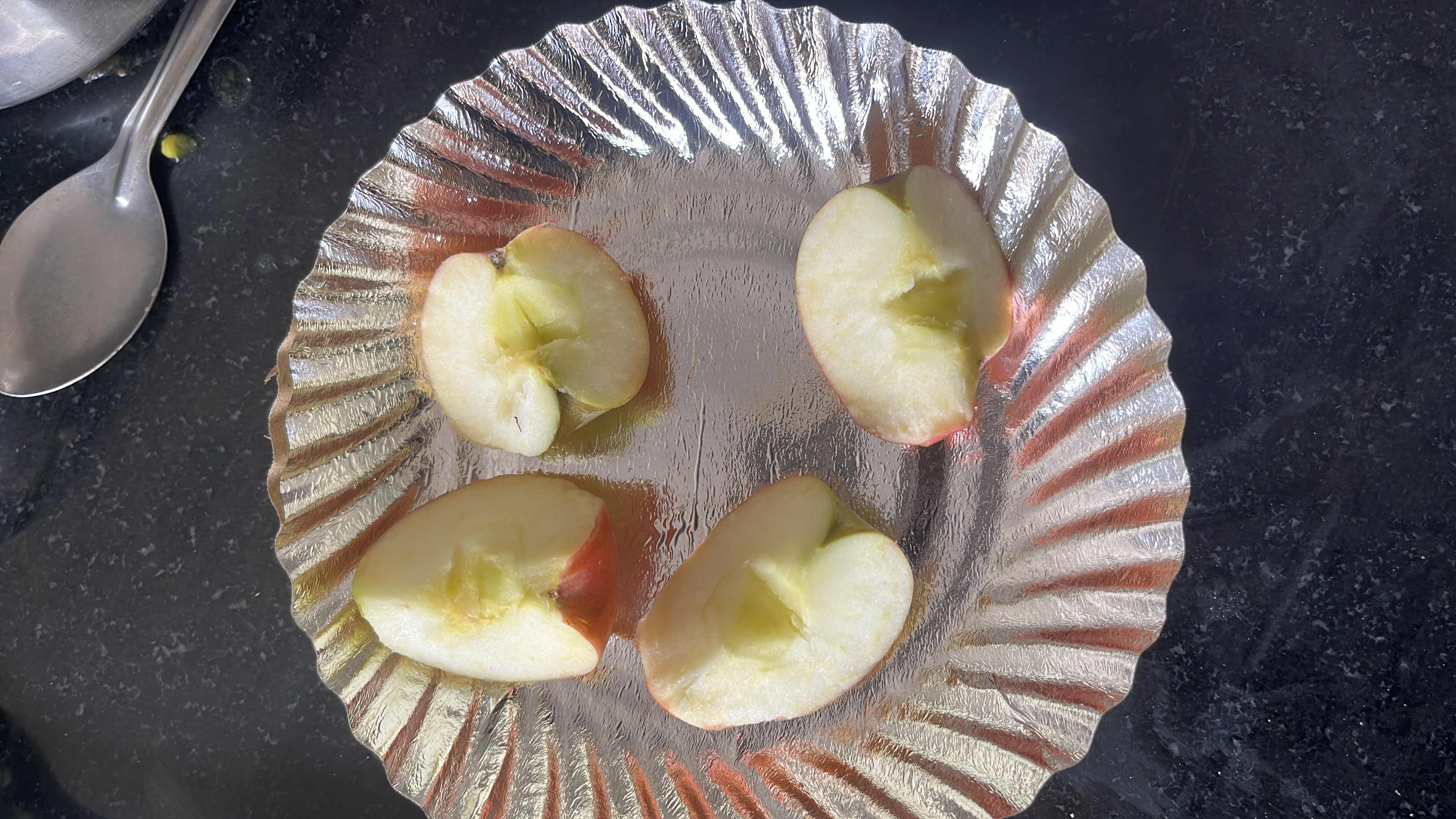 The image shows four slices of apple on a silver plate, a healthy and low-calorie fruit snack.
