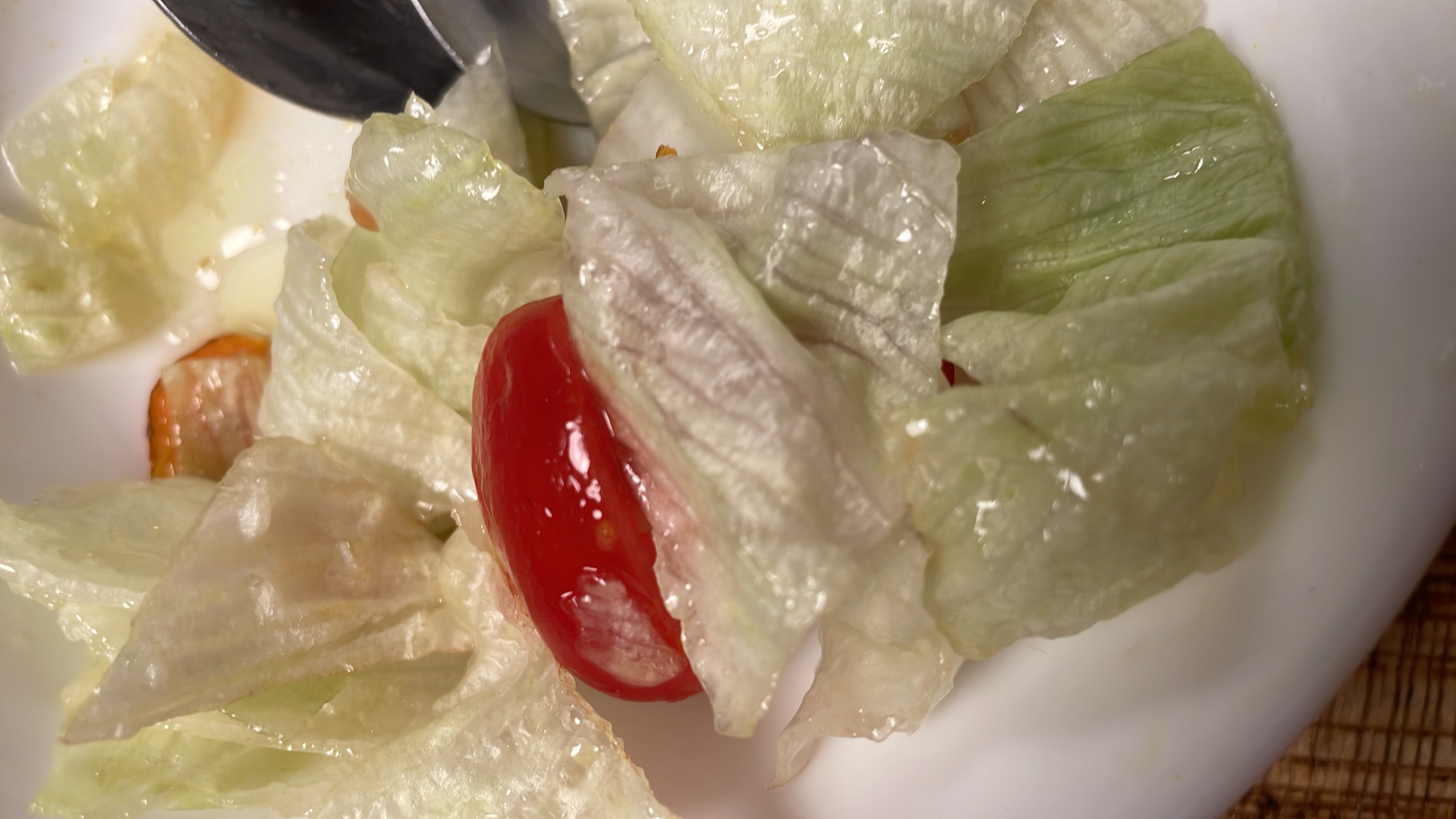 A salad with iceberg lettuce, tomatoes, turmeric, and a dressing of apple cider vinegar and olive oil, offering a healthy and flavorful option.