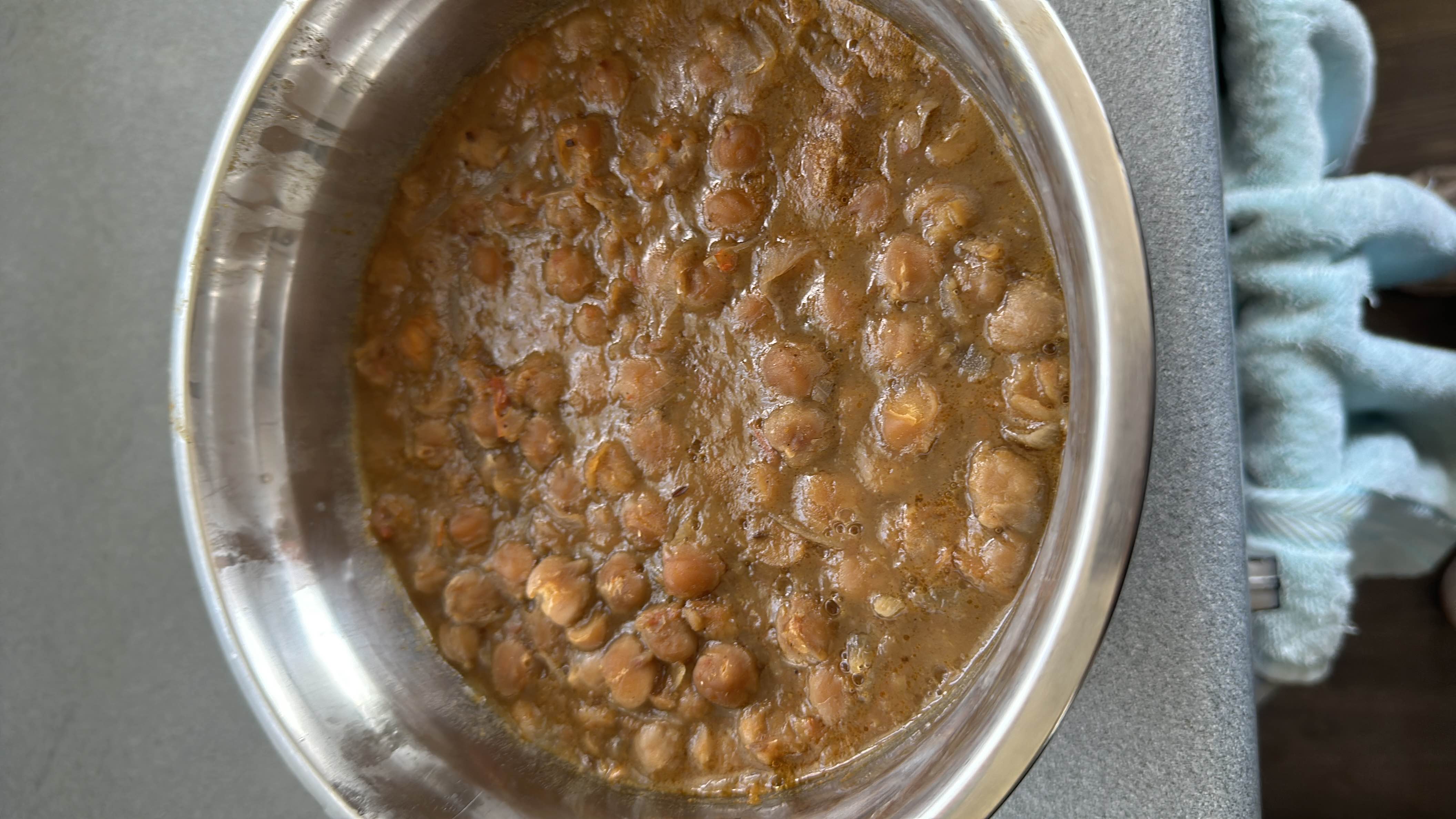 A bowl of cooked chickpeas in a spiced gravy, rich in protein and carbohydrates with moderate fat content.