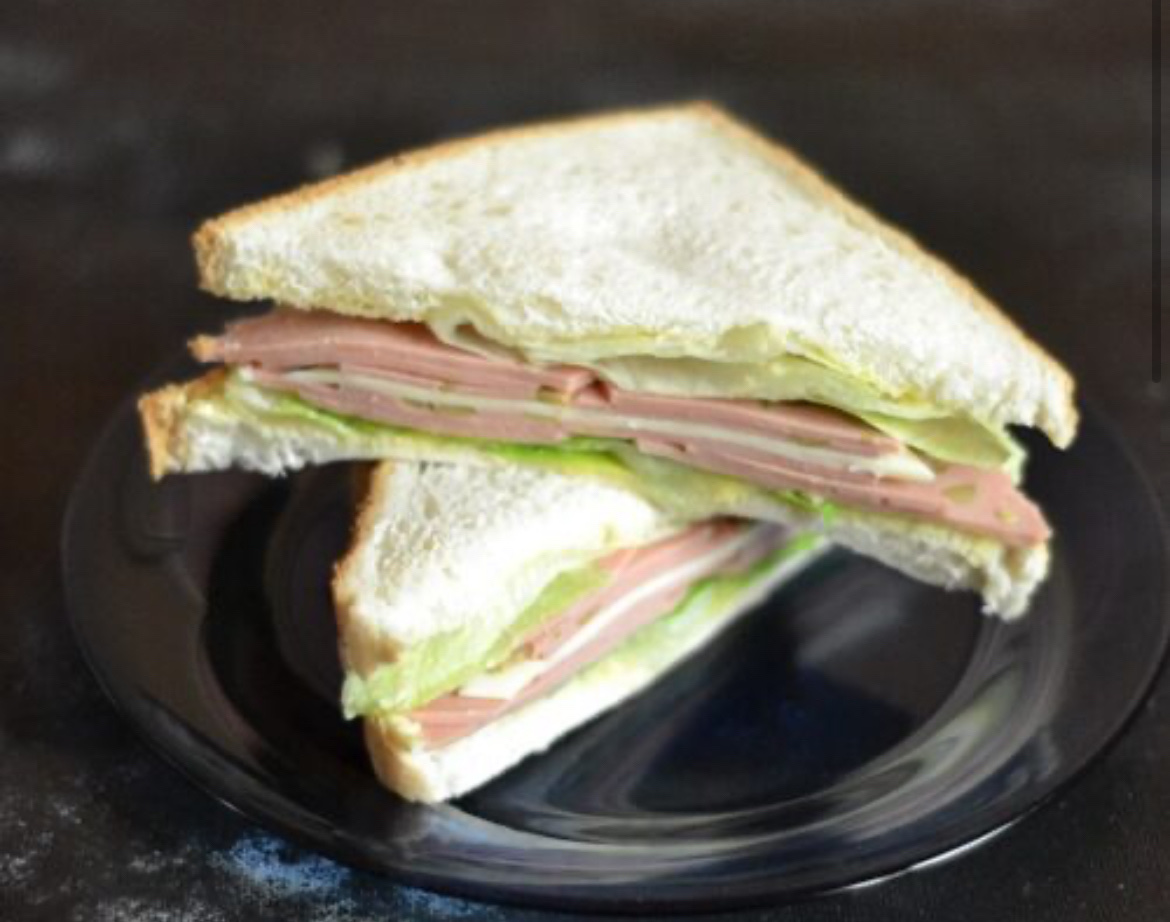 A ham and cheese sandwich with lettuce on white bread, providing a balanced mix of protein, carbs, and fats.
